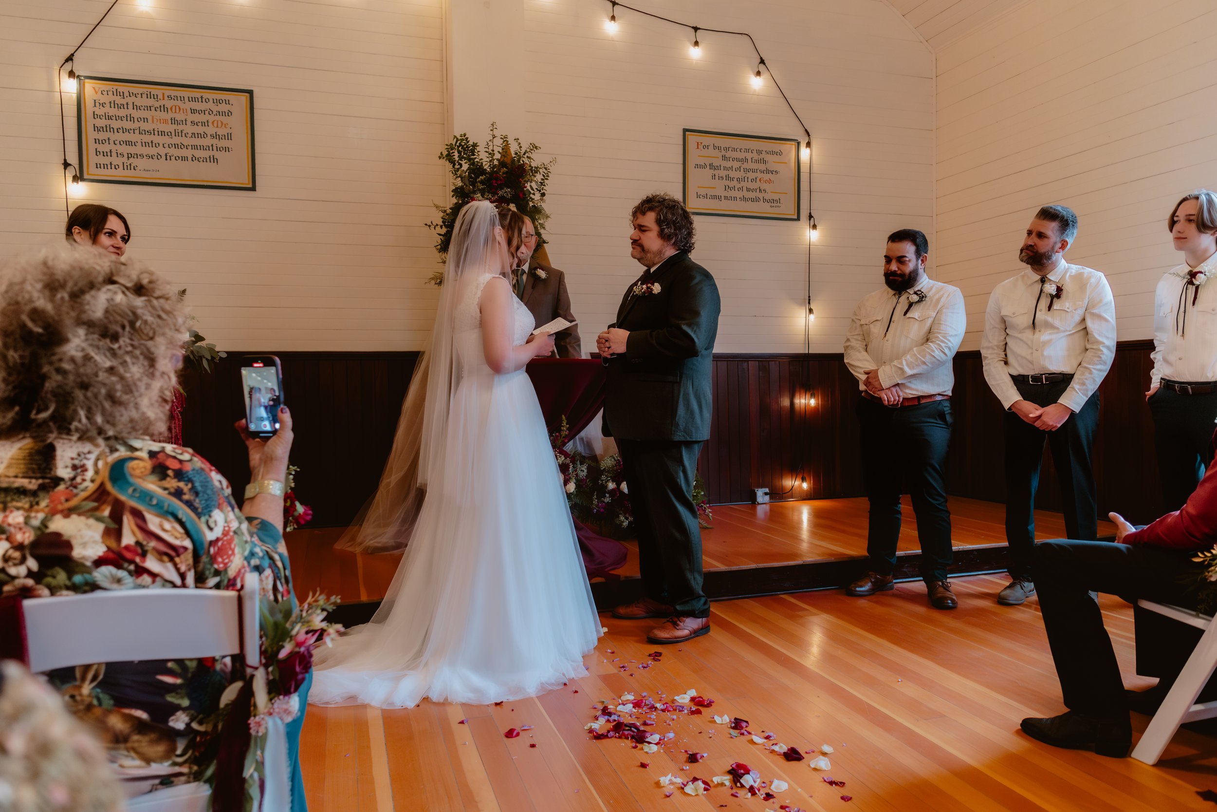 Bride and groom exchanging vows beneath a floral arrangement in the historic chapel