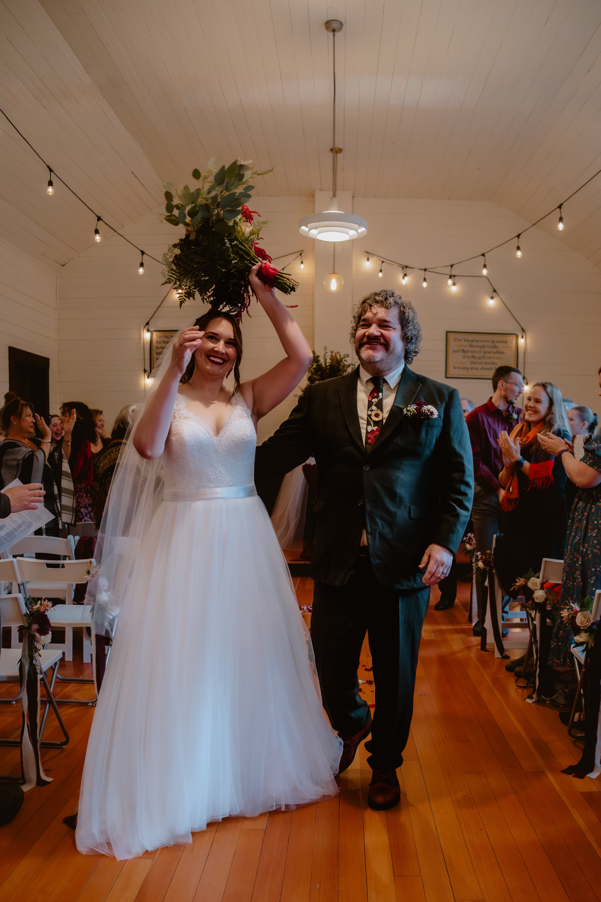 Bride celebrating with her bouquet while leaving the ceremony at Hummingbird Hall