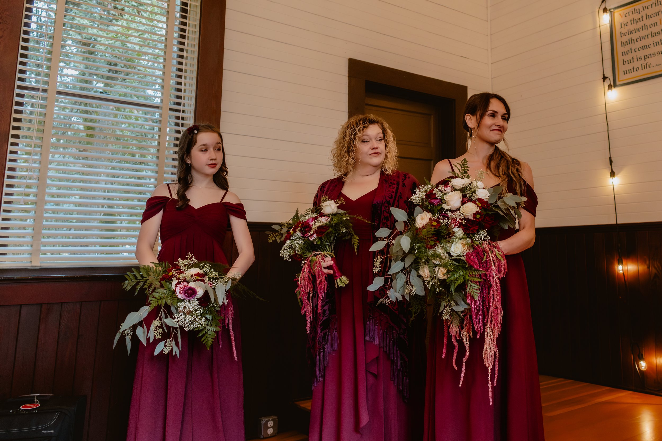 Bridesmaids in burgundy dresses holding fall wedding bouquets