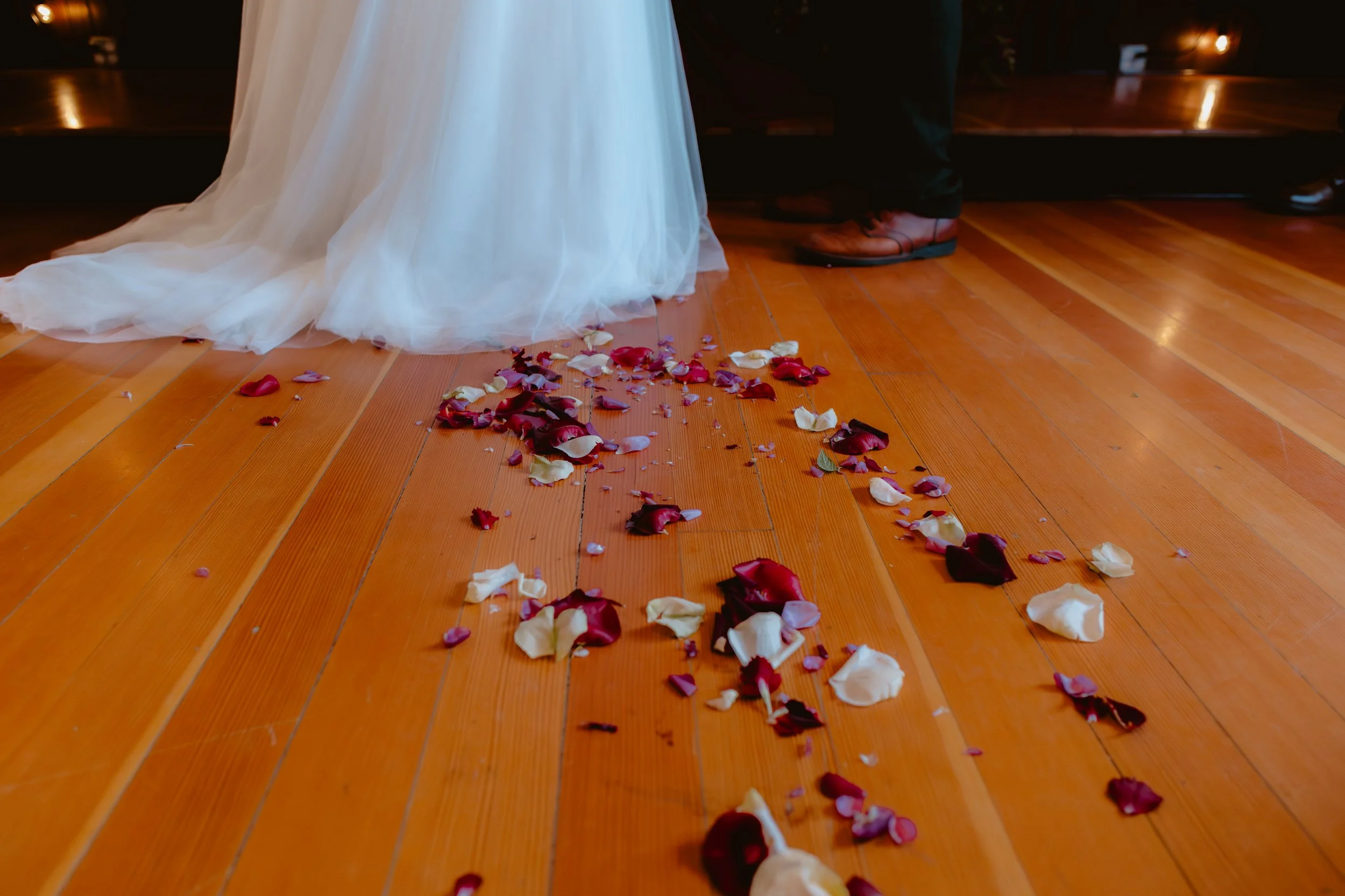 Rose petals scattered across the wood aisle during a fall wedding ceremony
