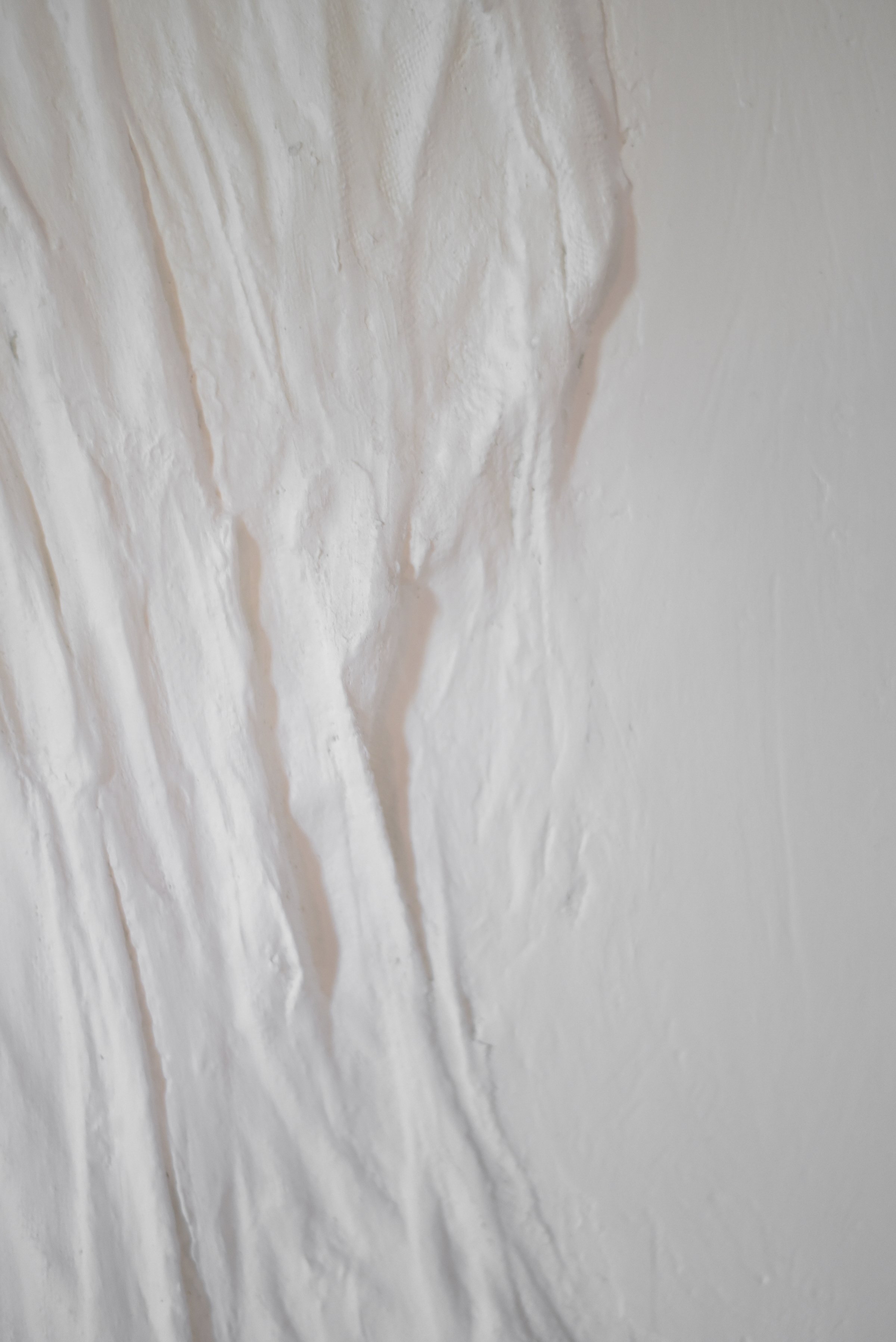 White textured wall with visible brush strokes and paint drips.