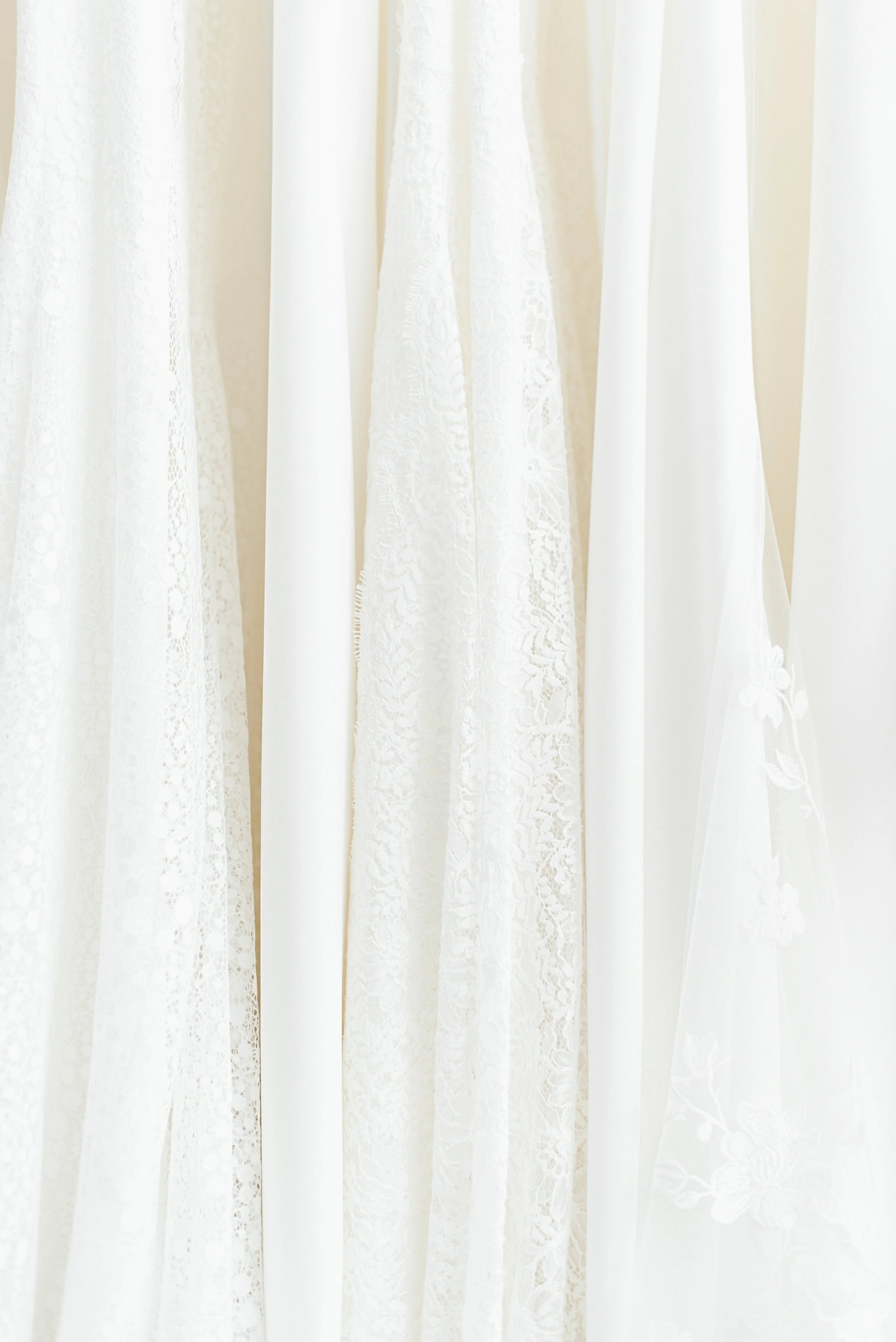 Close-up image of white lace and sheer curtains with floral patterns.