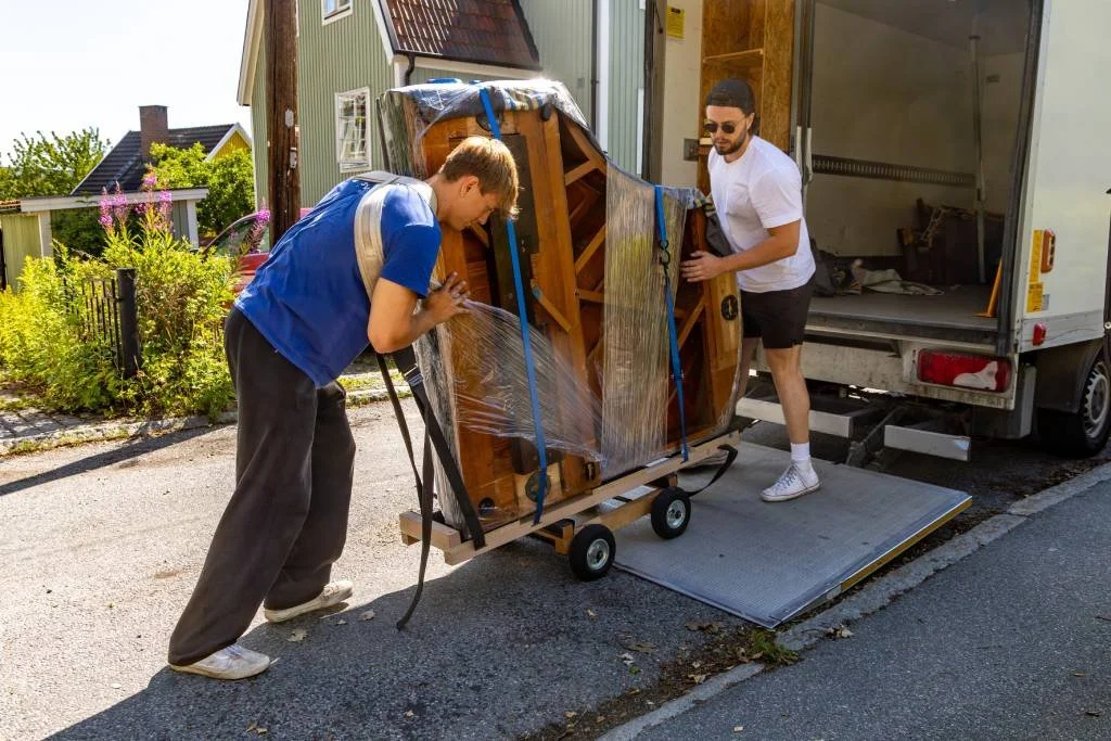 Workers loading a piano onto a truck.
