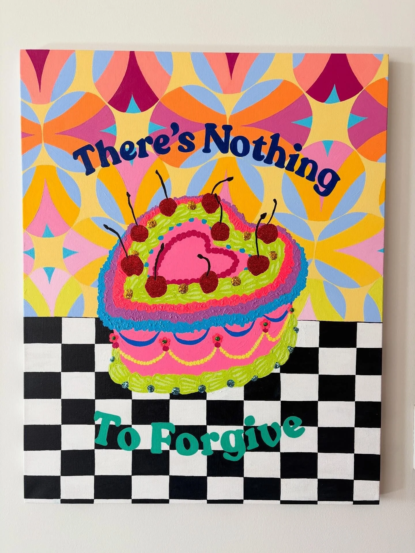 Colorful poster with a pink cake topped with cherries on a black and white checkered tablecloth. The background has a yellow, pink, blue, and purple geometric pattern. Text reads "There's Nothing To Forgive".