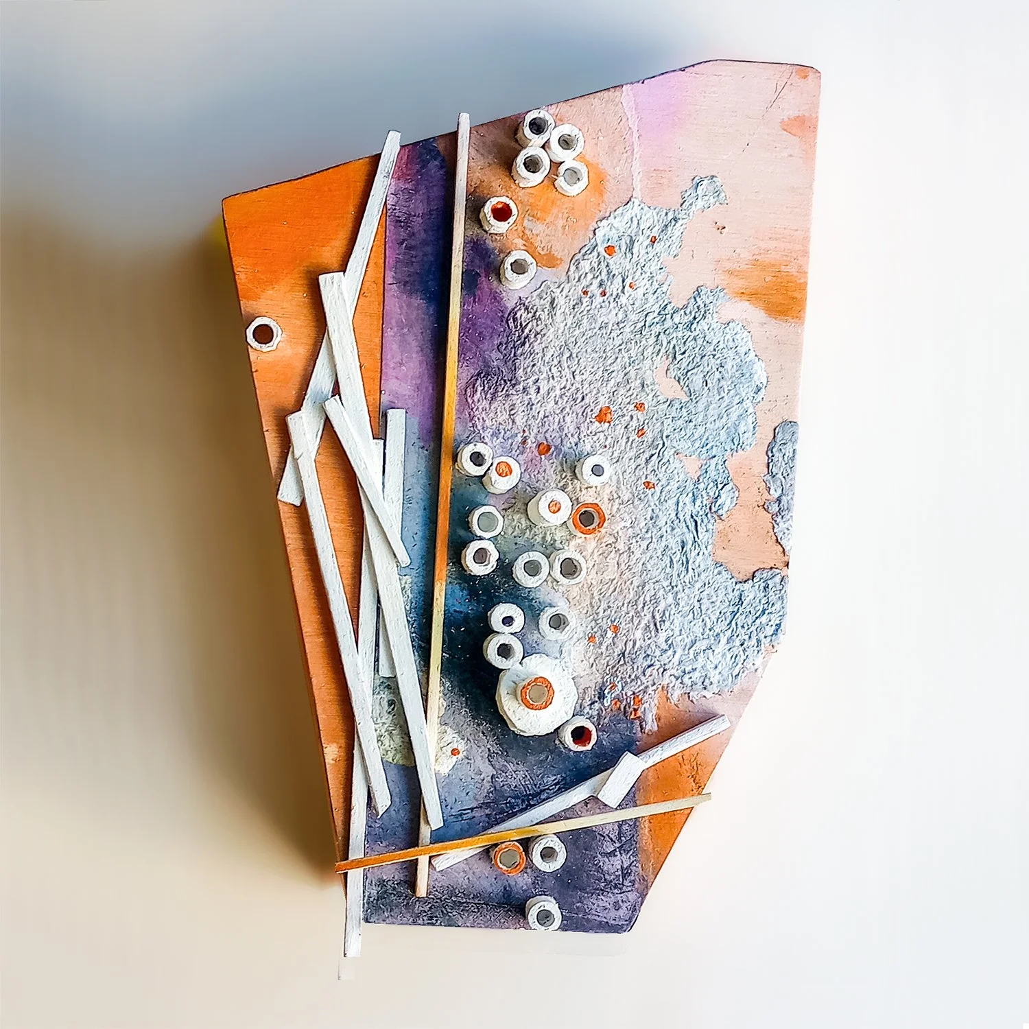 Abstract mixed media wall sculpture with wood pieces, painted in warm tones.