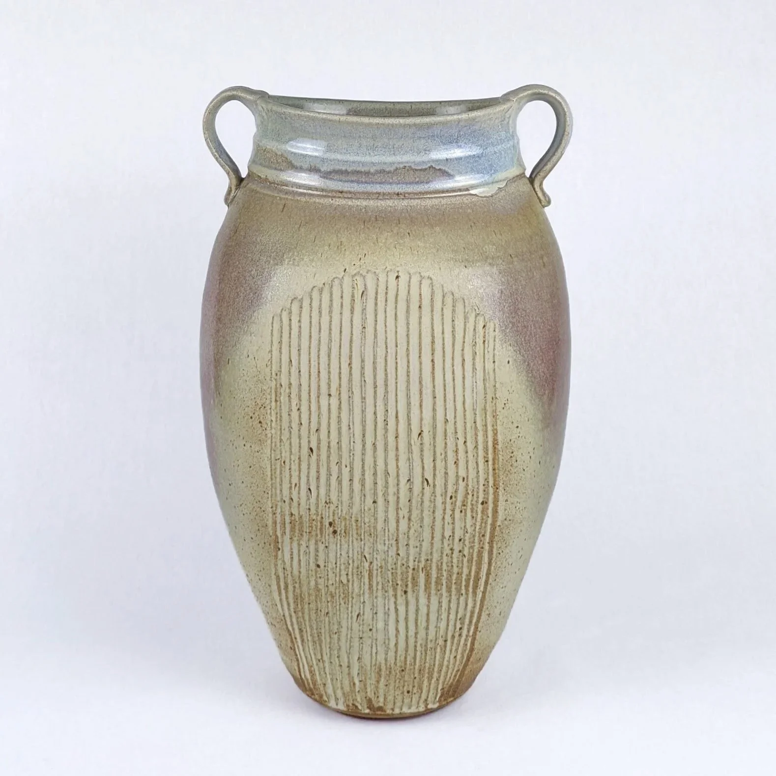 A ceramic vase with a narrow bottom that widens towards the top, featuring two small handles on either side and a textured, ribbed design on its surface.