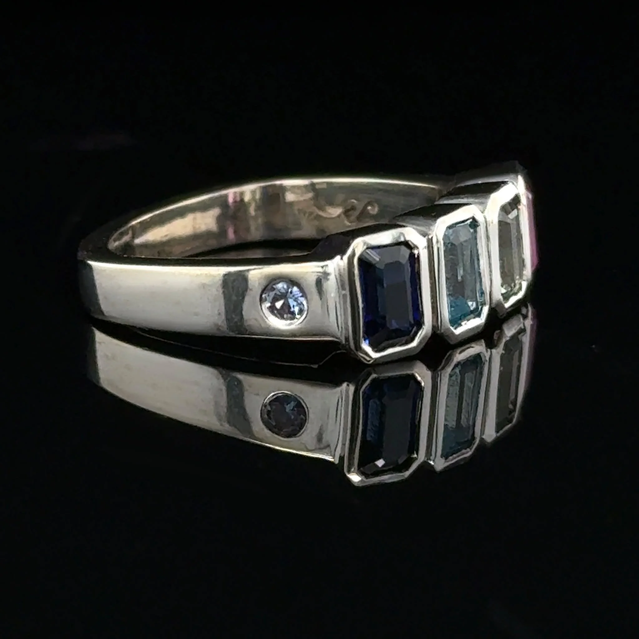This custom bezel-set family ring comes with a little surprise. All of the stones are lab-created sapphires, which means we get access to a whole new world of colour. The light green and soft blue up top are newly developed shades, and they absolutel