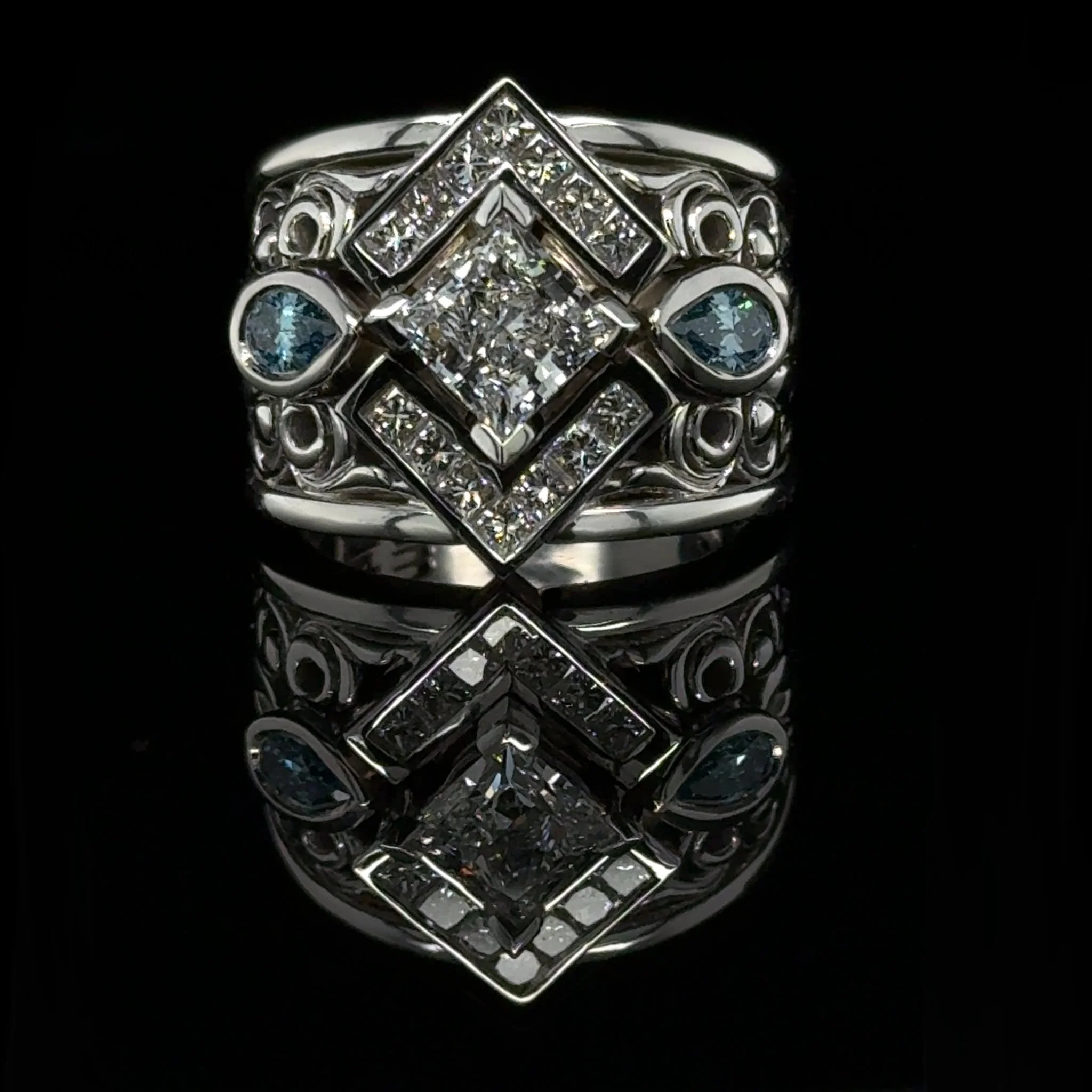 This client came in with an older ring ready for an upgrade. The original stones beautiful high grade natural diamonds and along with the updated design we added a pop of colour with  blue pear-shaped lab diamonds on the side. The filigree detailing 