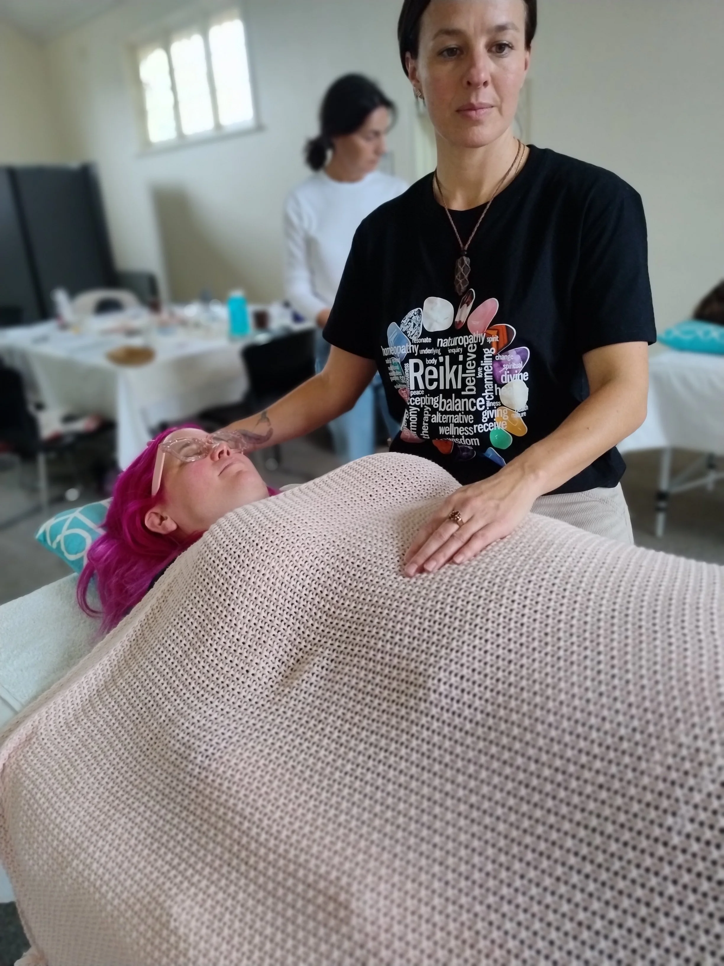 Usui Reiki teacher Kaliesha demonstrating gentle hand placements on a massage table during a training course in Adelaide.