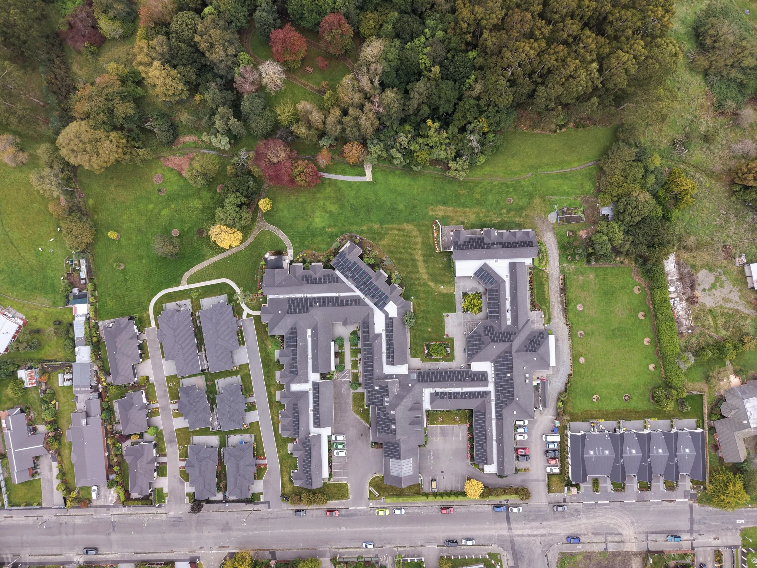Aerial view of a residential complex with multiple apartment buildings, parking lots, green lawns, and trees.
