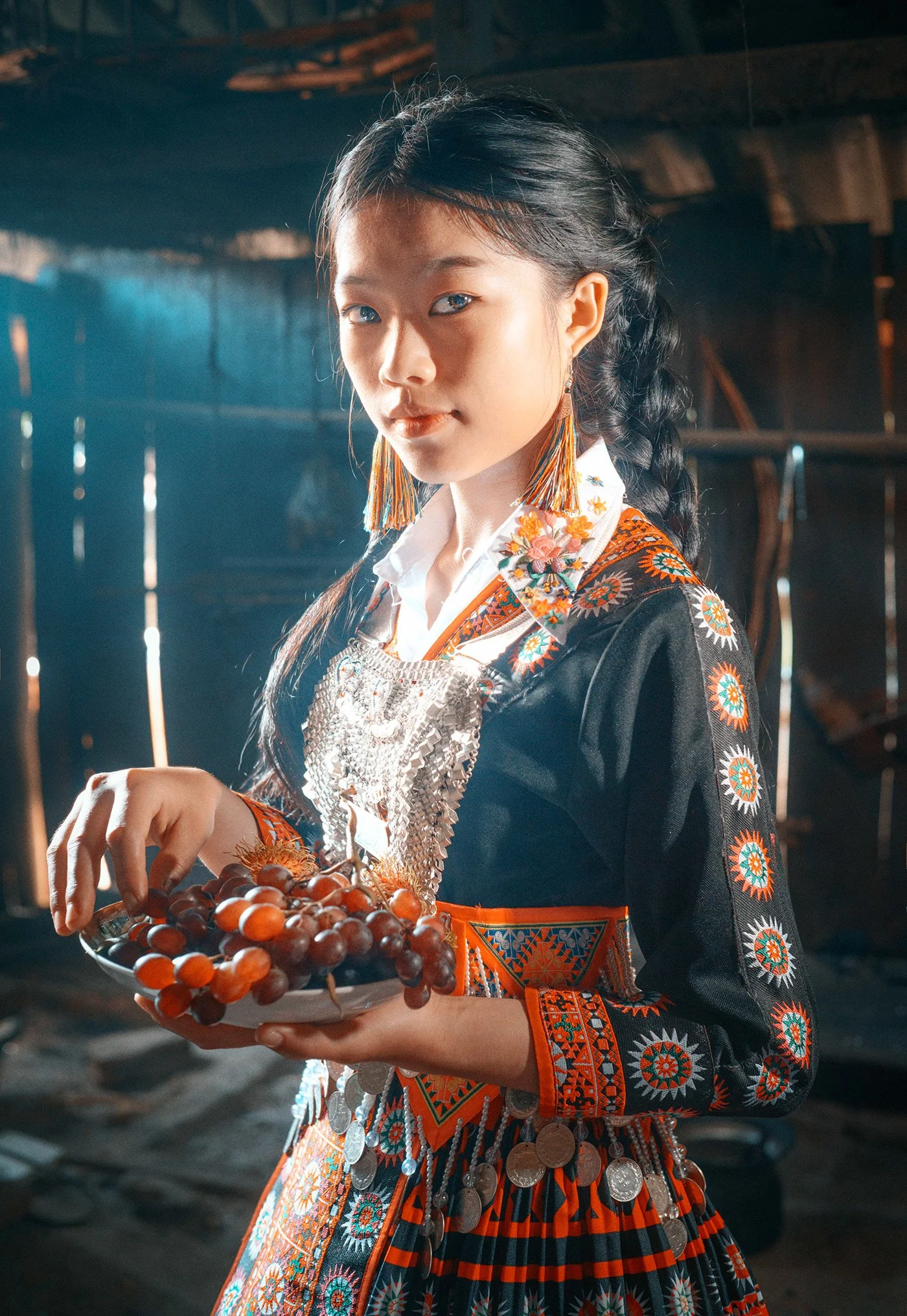 Femme en costume traditionnel avec des bijoux en argent, tenant un plateau avec des raisins.