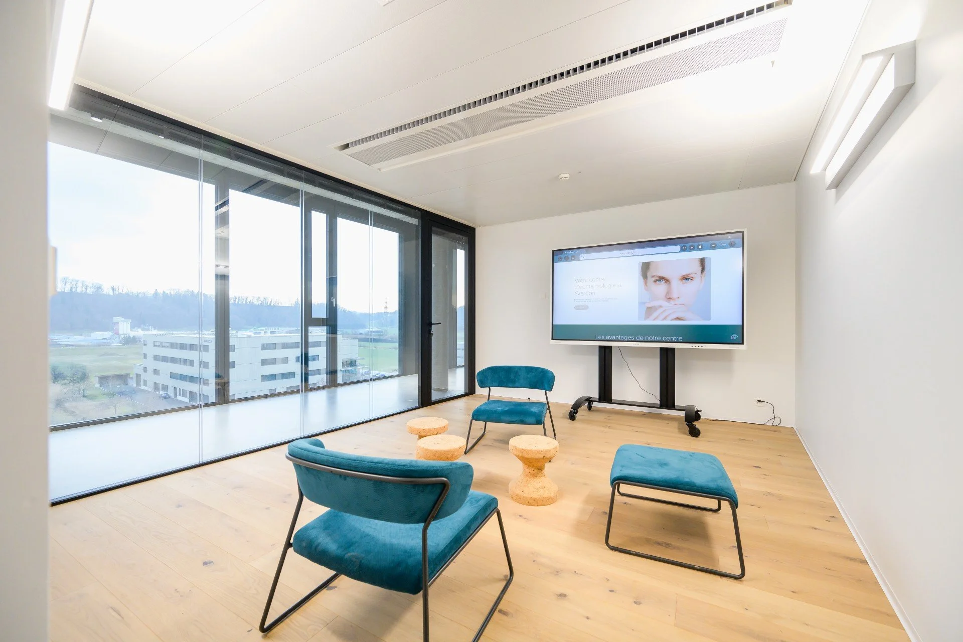 Salle de réunion avec planché clair, chaises en velour et grand écran intéractif