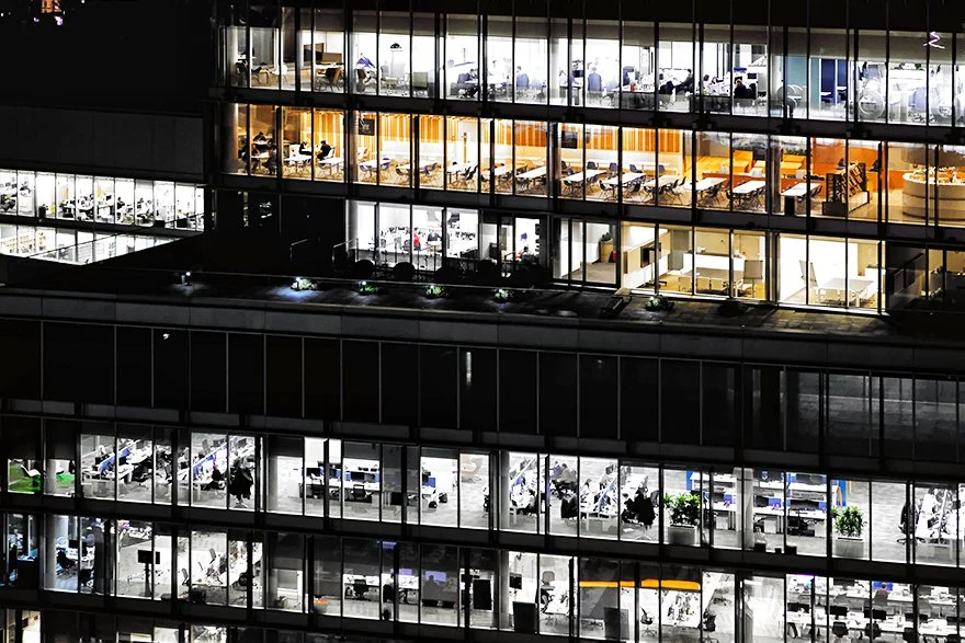 London office building at night with lights on and people working