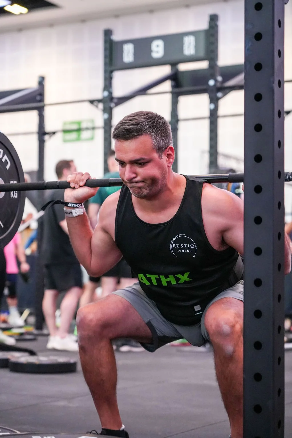 A metal tiny house with a wooden frame doorway, surrounded by greenery, with a small metal staircase leading to the entrance.