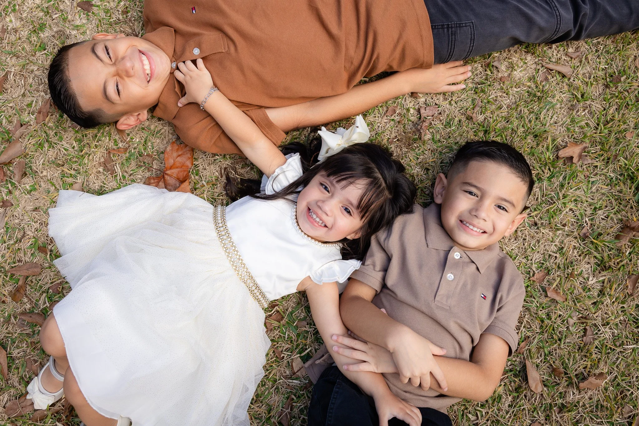 A group of children lying on the grass, smiling and enjoying their time outdoors.