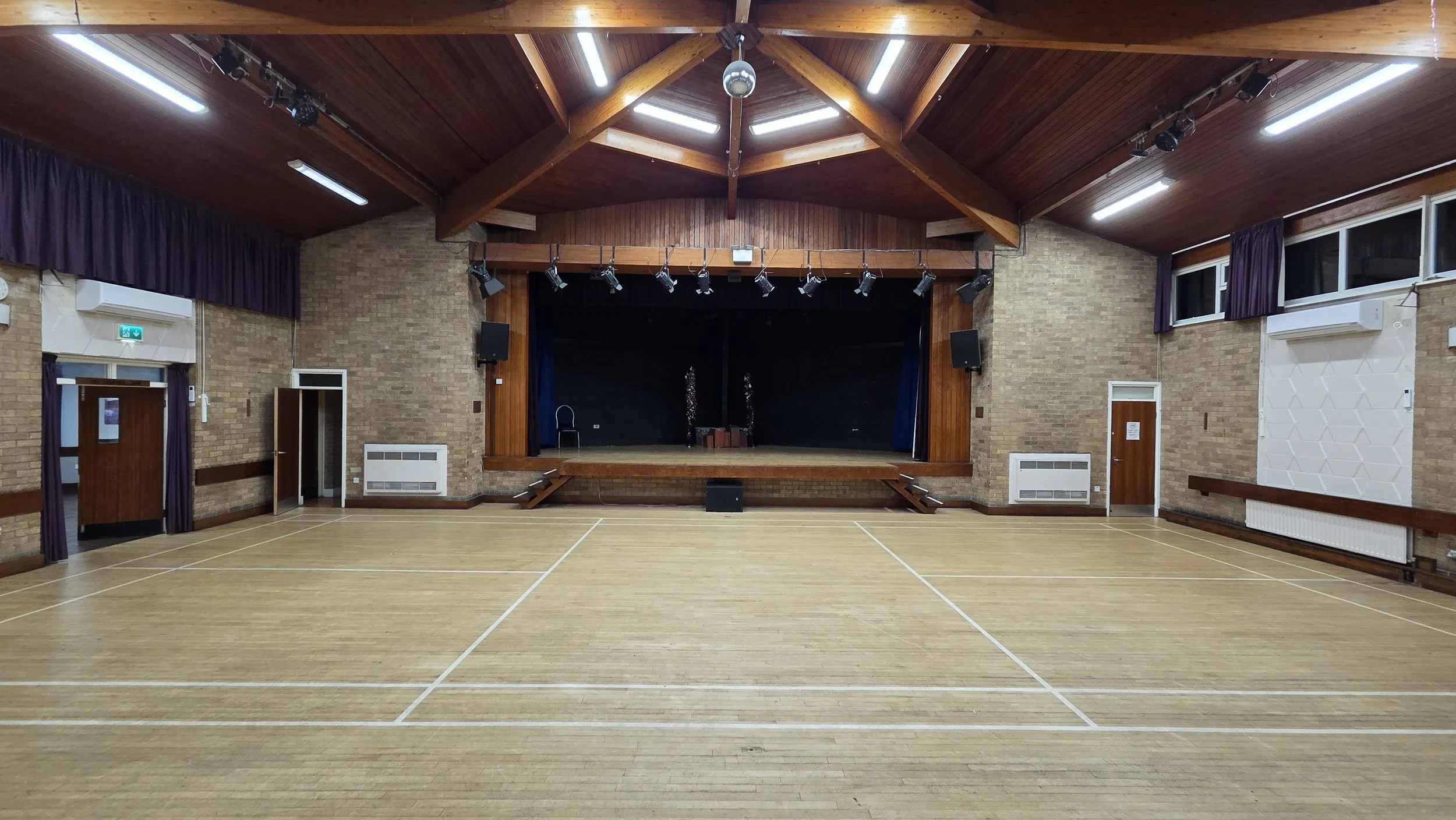 This is the main hall which is slightly larger than a badminton court size. The stage is at the front and the Brammer Room is through the double doors on the left. The single doors either side of the stage lead to backstage and the stage undercroft u