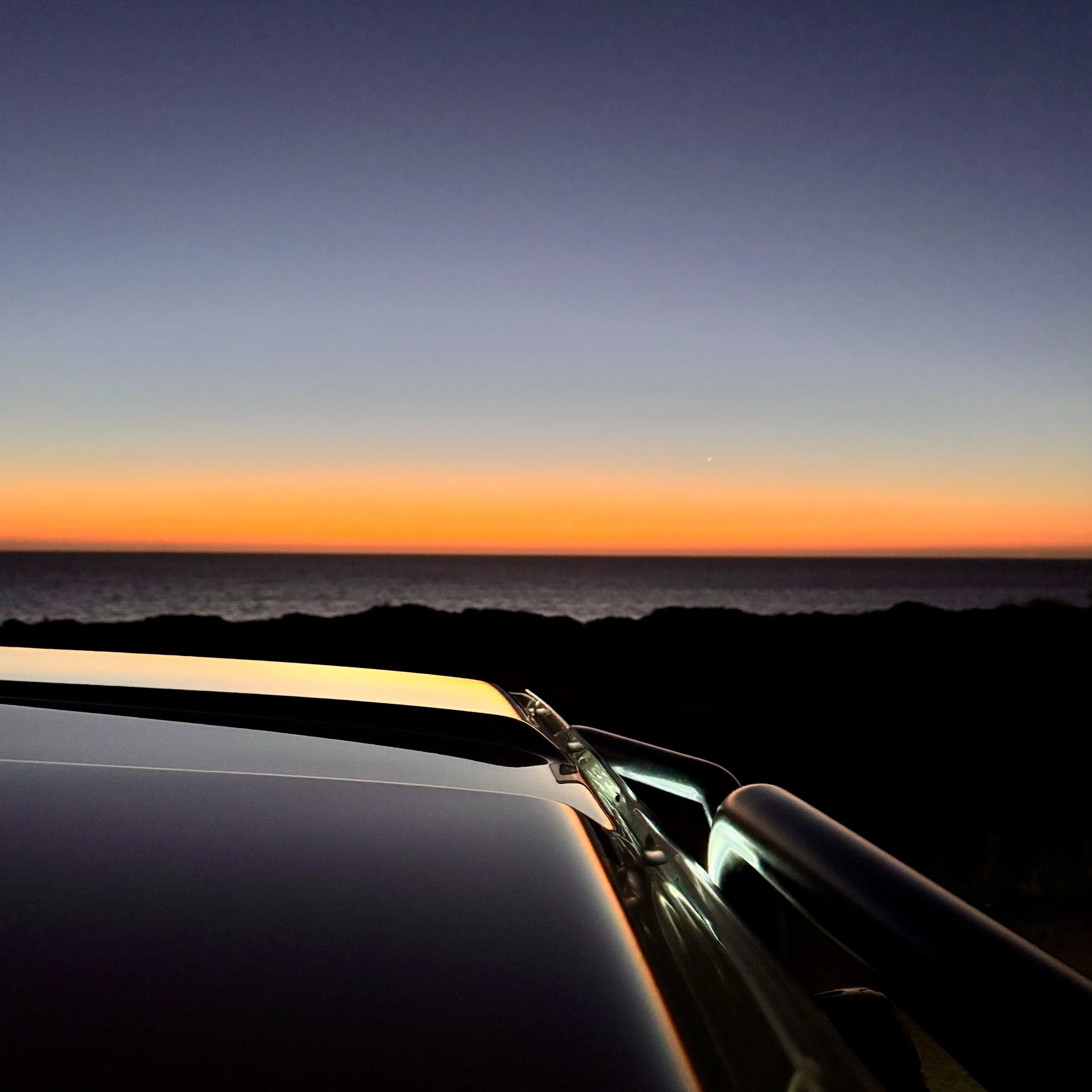 Late sunset over a car bonnet on the Indian Ocean coastline