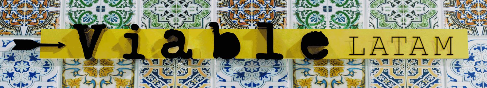 Cartel amarillo con letras negras que dice 'Vía b1 LATAM' en un fondo de mosaicos azules, blancos, verdes y amarillos con motivos geométricos.