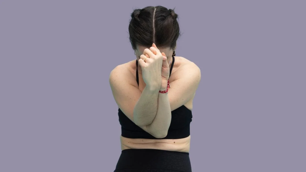 Rada Yoga with eagle arms, wearing black yoga clothes