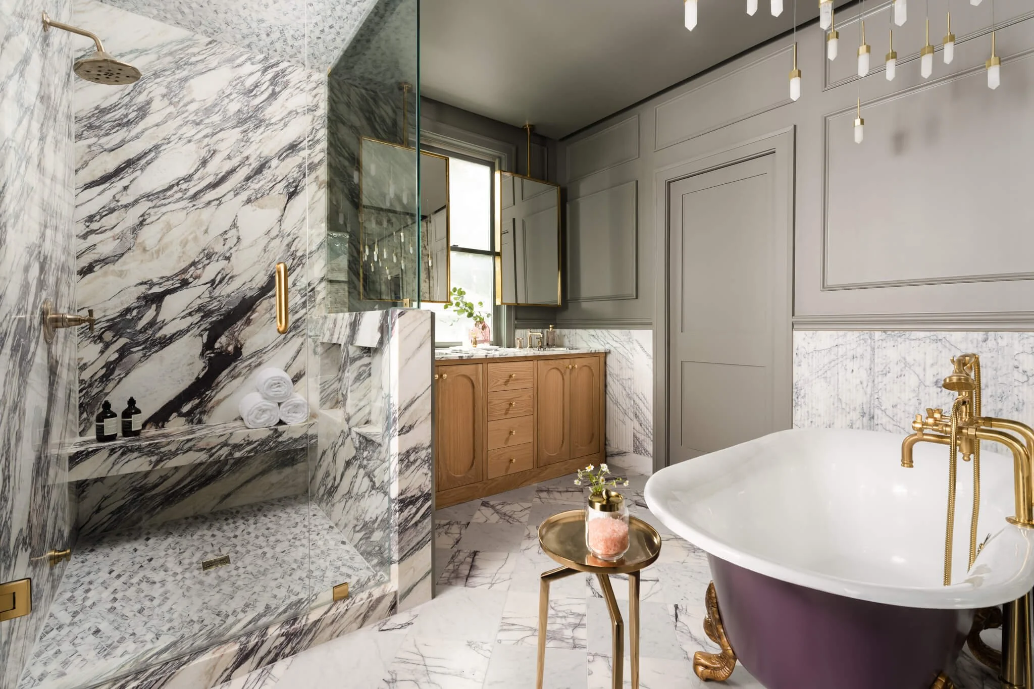 Marble bathroom interior with freestanding soaking tub, walk-in shower, and warm wood vanity photographed in Dallas.