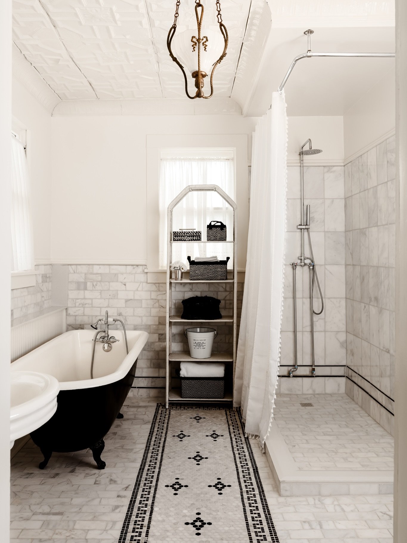 There&rsquo;s something lovely about a bathroom that honors the history of a home while simultaneously embracing modern living.

Original character, like the pressed tin ceiling and black clawfoot tub, joins classic materials: marble tile, polished c