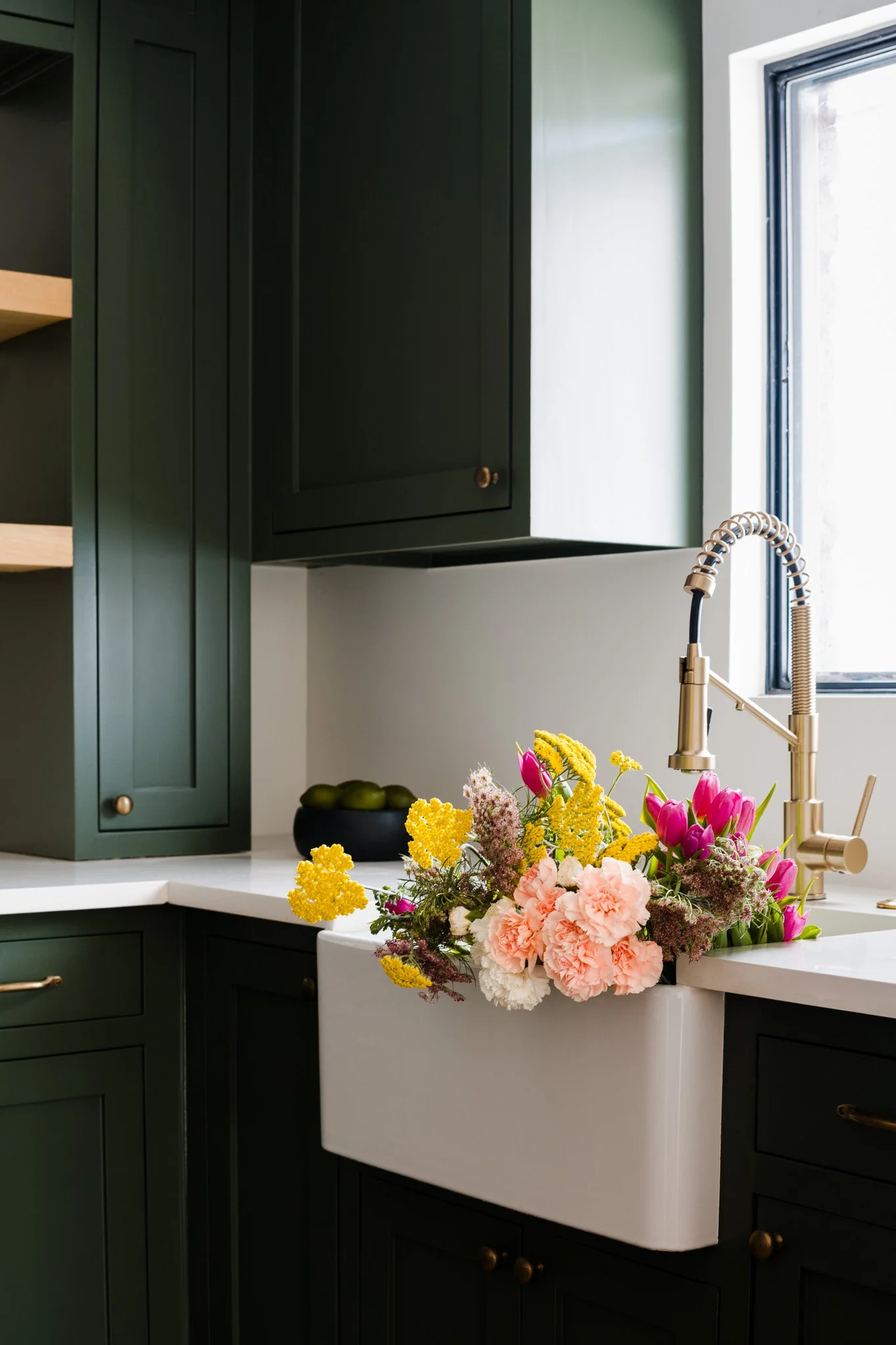 Green kitchen corner with farmhouse sink and floral arrangement