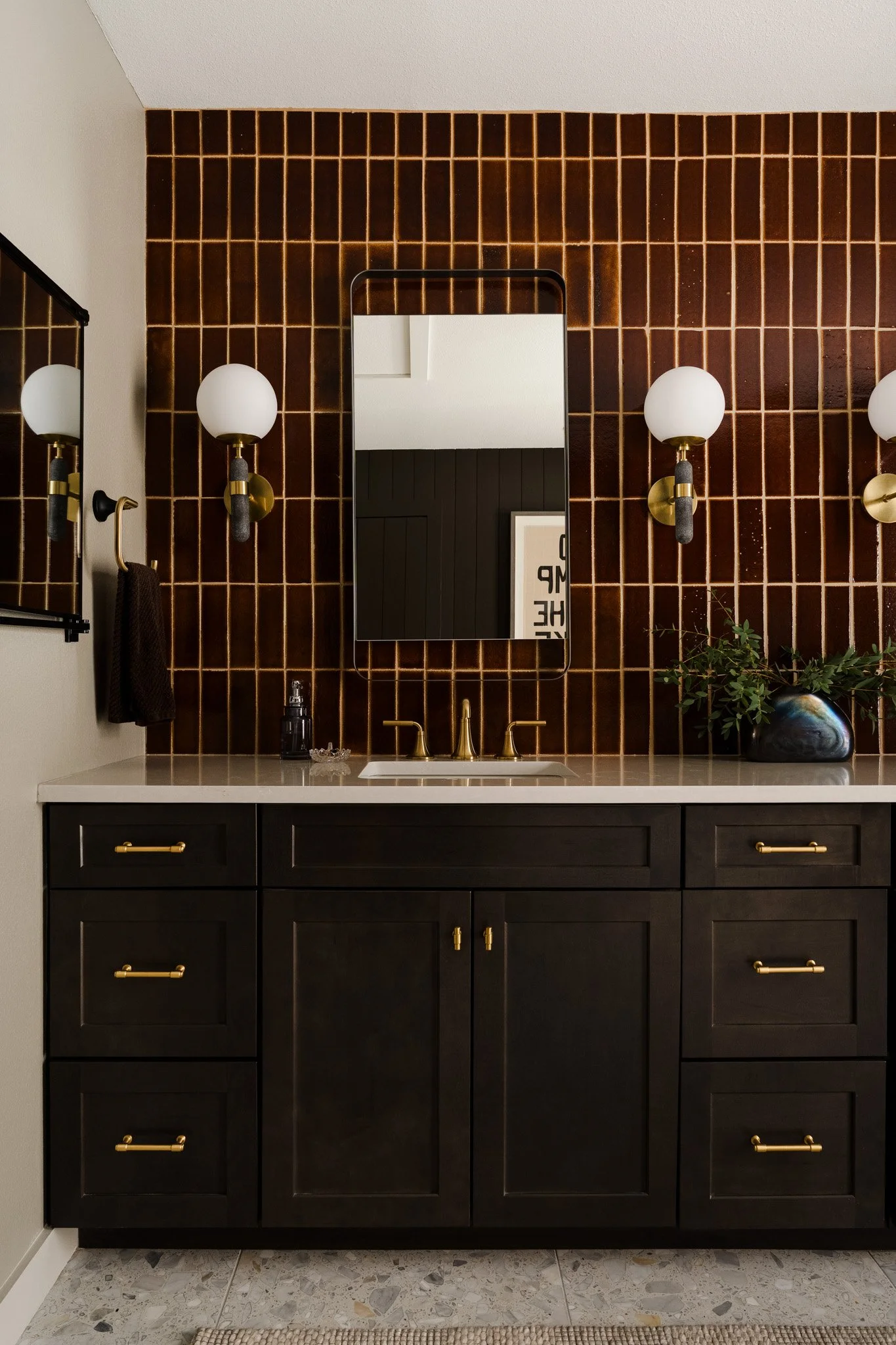 Dark wood bathroom vanity with brass hardware and tile backsplash. Design by Sey Interiors 
