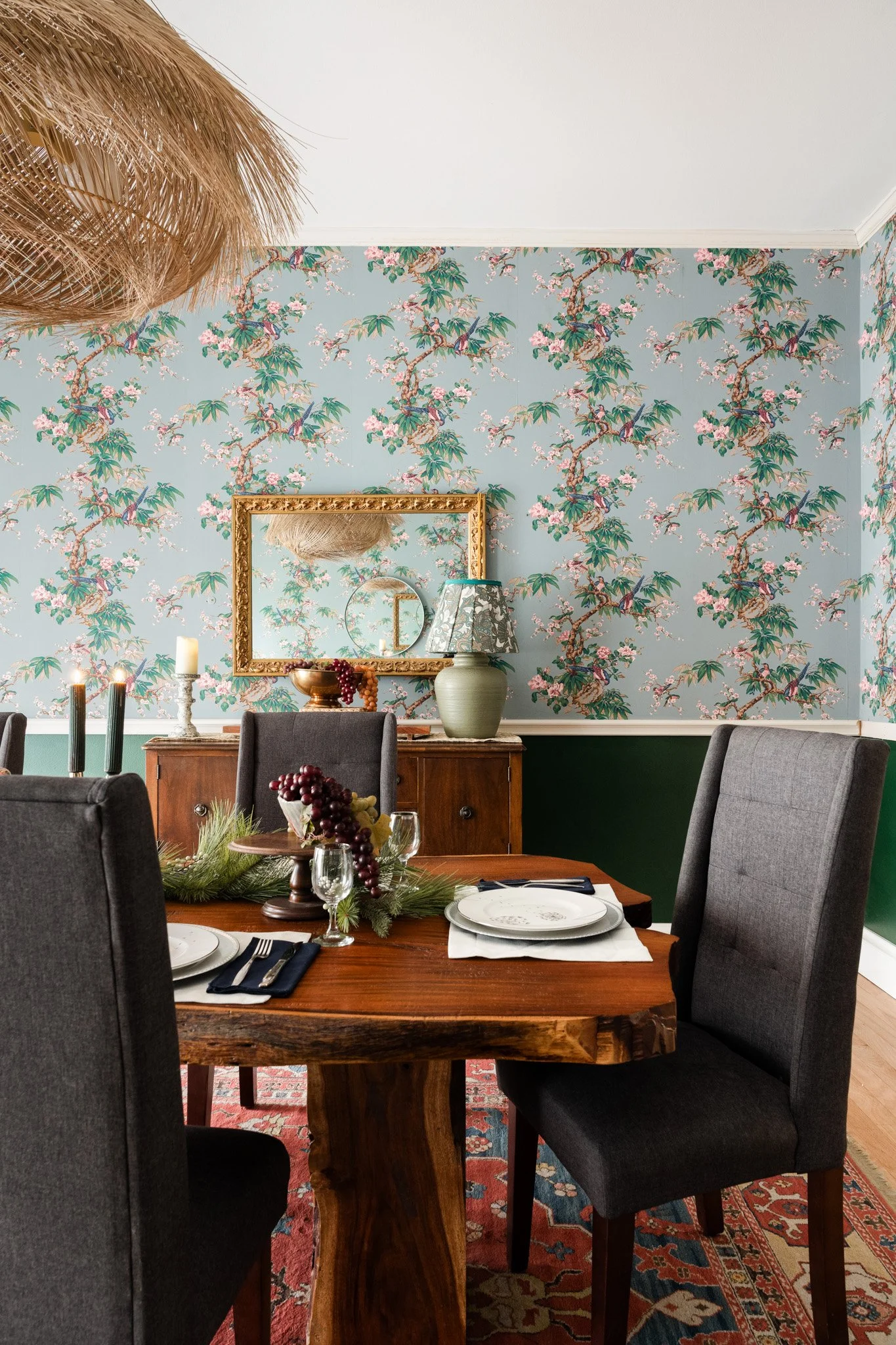 Grandmillennial dining room featuring floral wallpaper, a rattan light fixture and antique furniture. Design by Deann Pool Interiors 