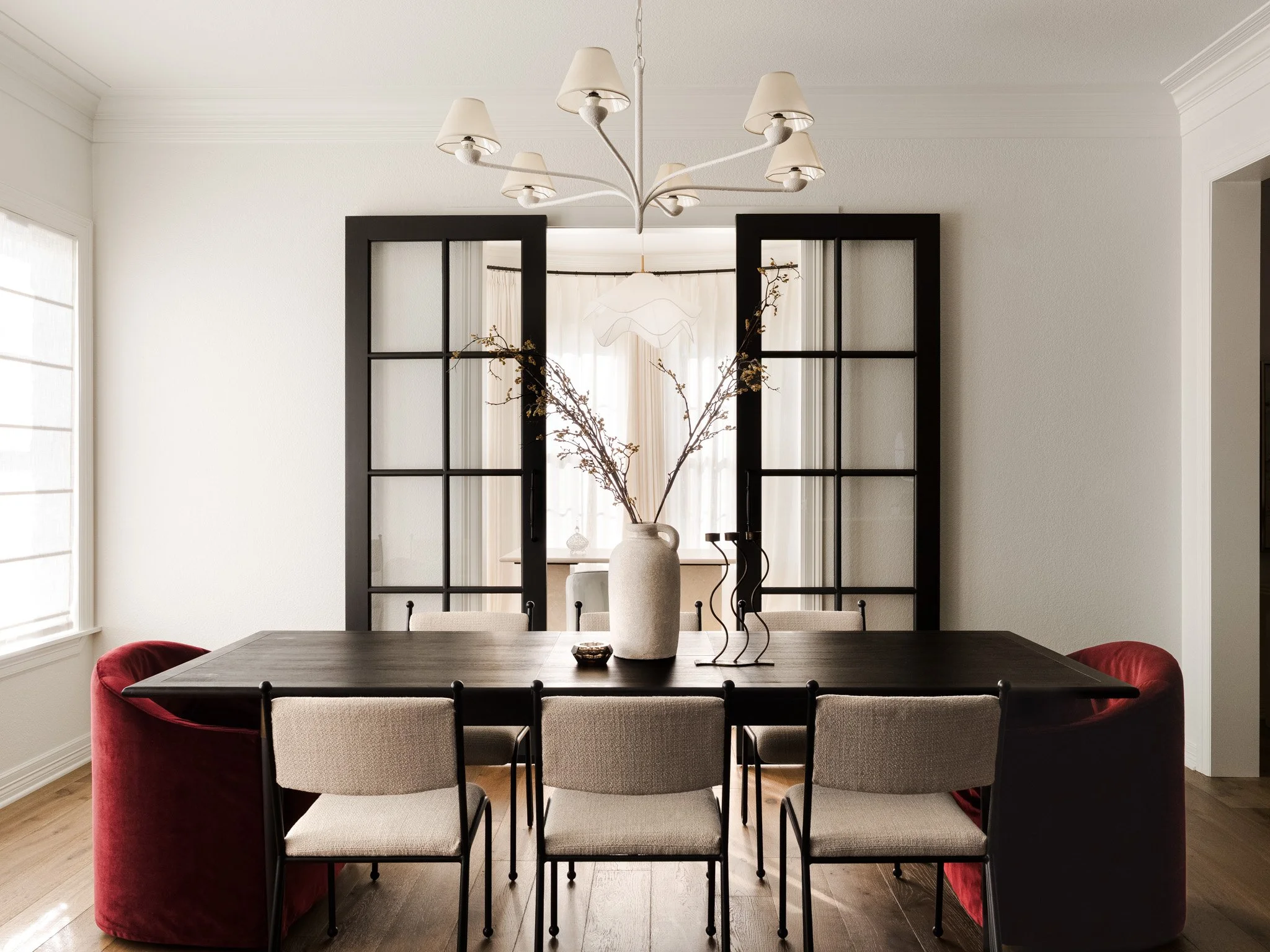 Dining room with black table, red velvet chairs, and glass-paneled doors. Design by Brittney Lane Interiors 