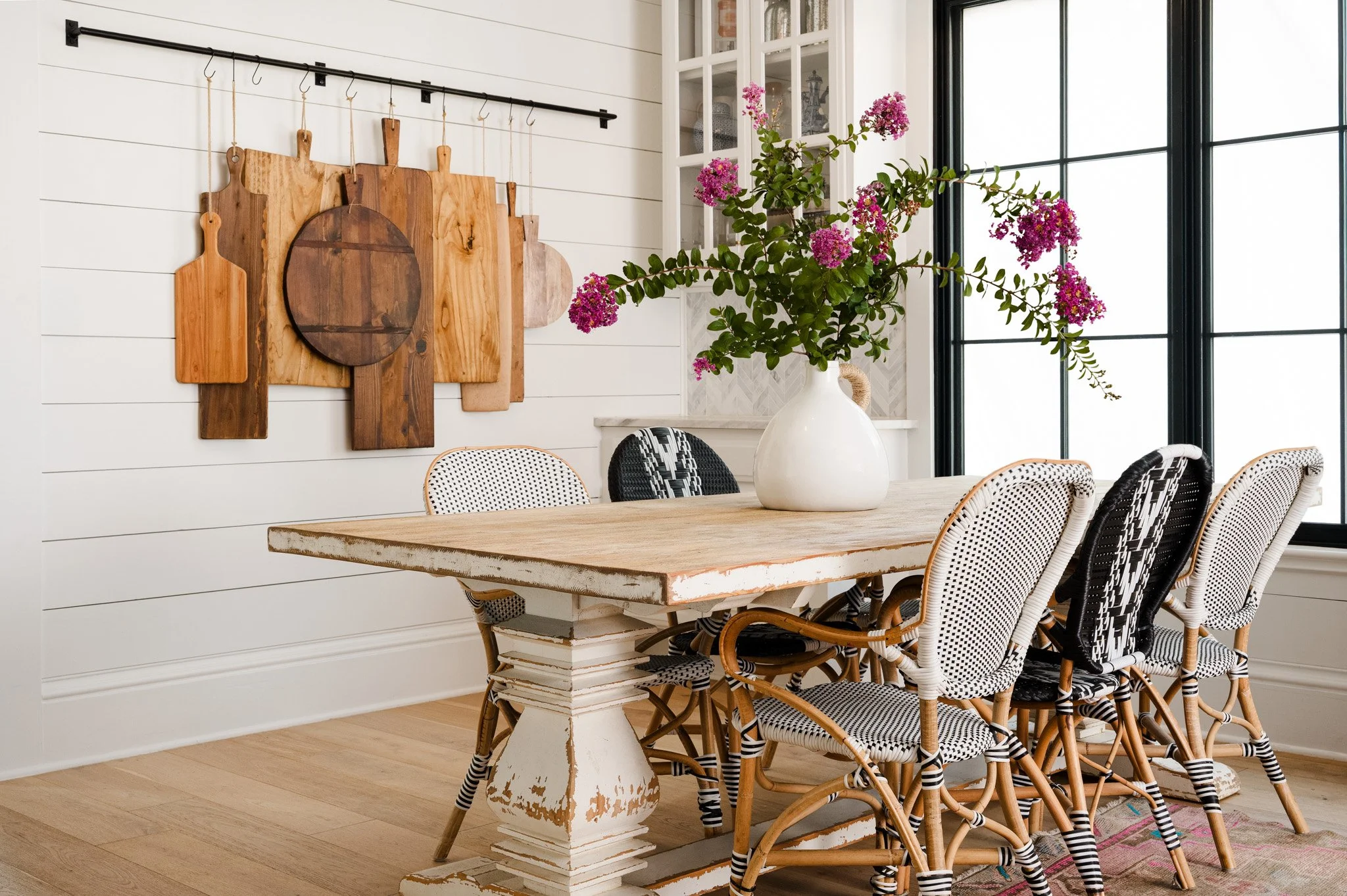 Light-filled dining room with rustic wood table and woven chairs. Design by Brittney Ratto 