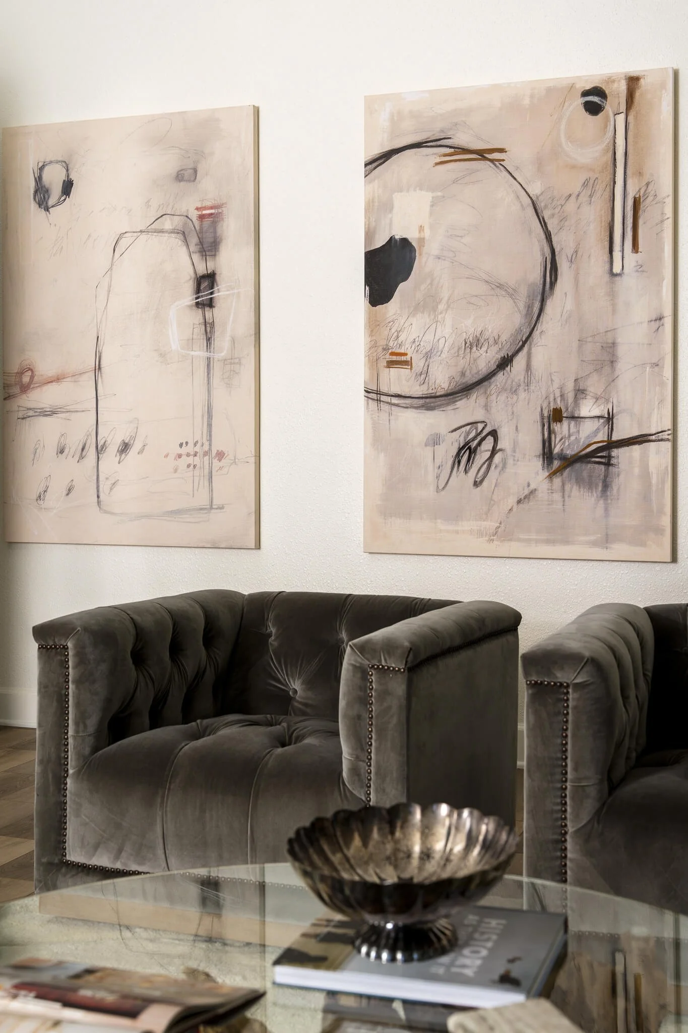 Modern cottage living room featuring tufted velvet club chairs, modern art, and natural wood slab coffee table with glass top