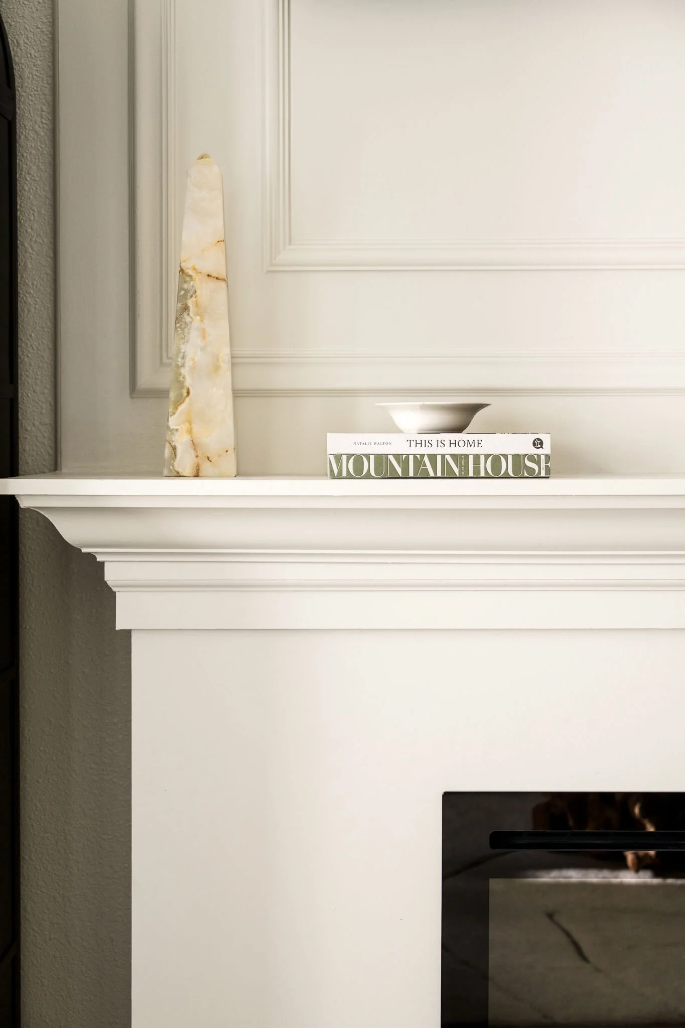 Fireplace detail showing decorative moulding, books, and a statue wall art Austin Texas Interior Design Photographer