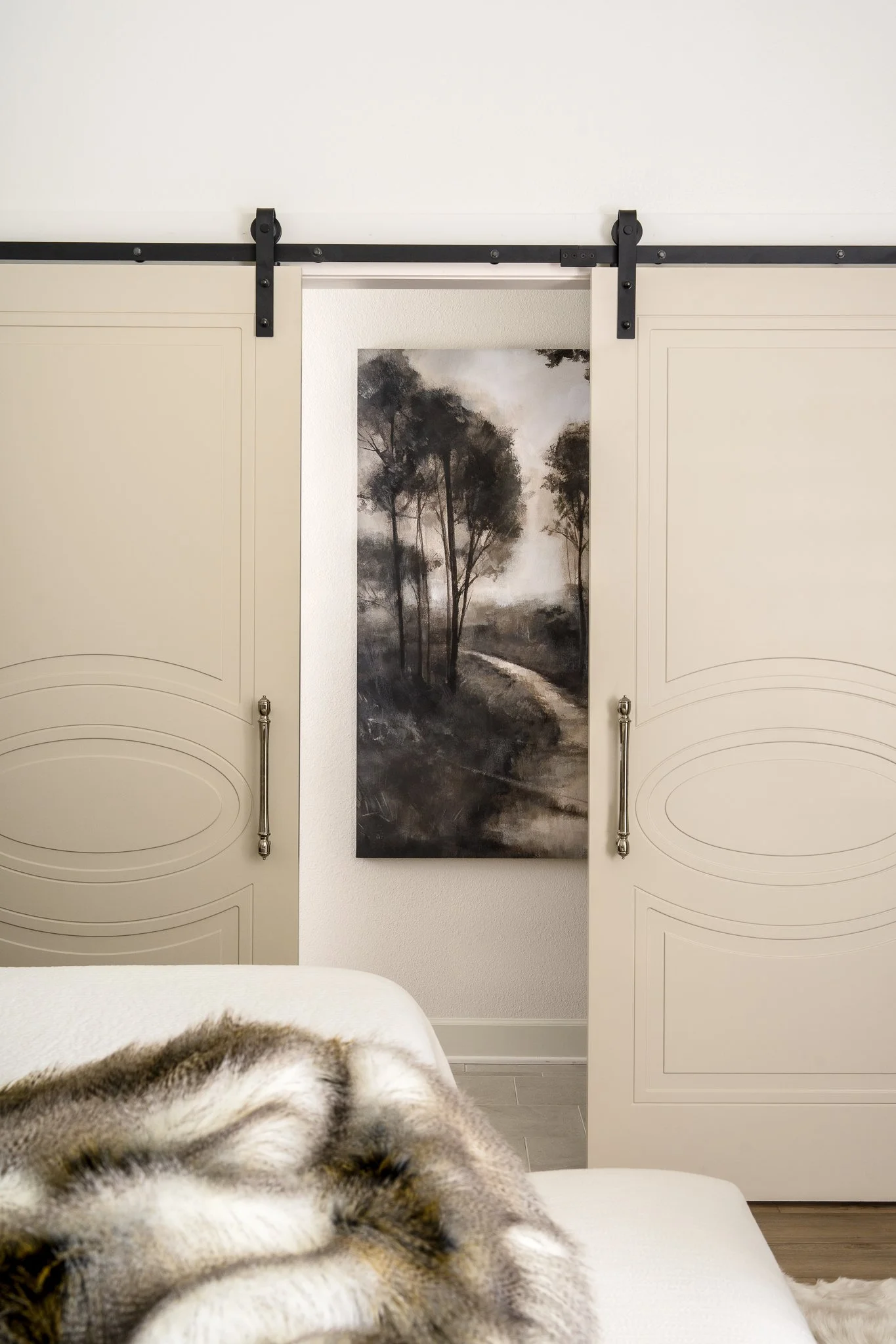 Austin interior photographer captures traditional bedroom with tray ceiling, cozy throw blankets, and barn doors.