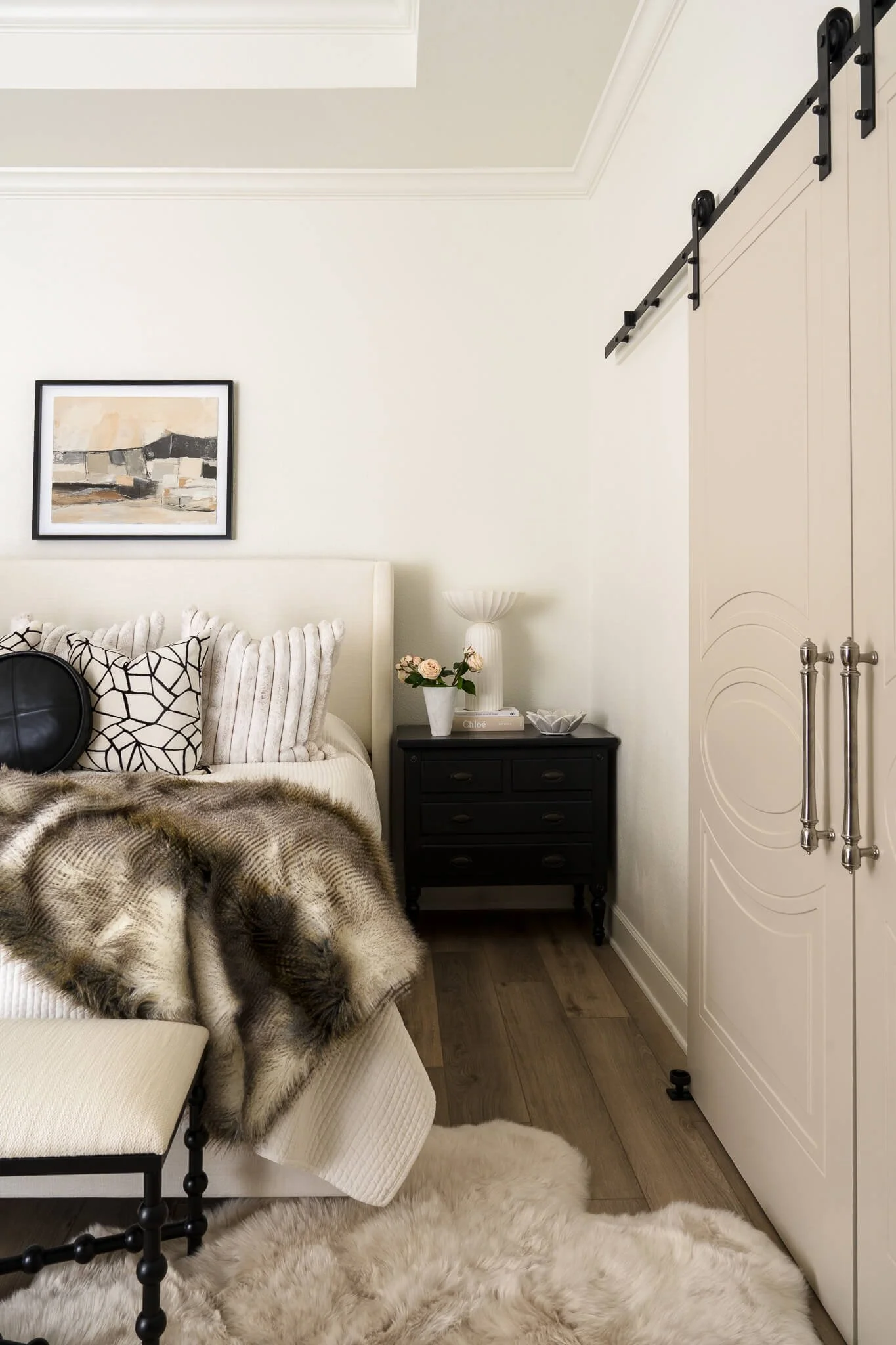 Austin interior photographer captures traditional bedroom with tray ceiling, cozy throw blankets, and barn doors.