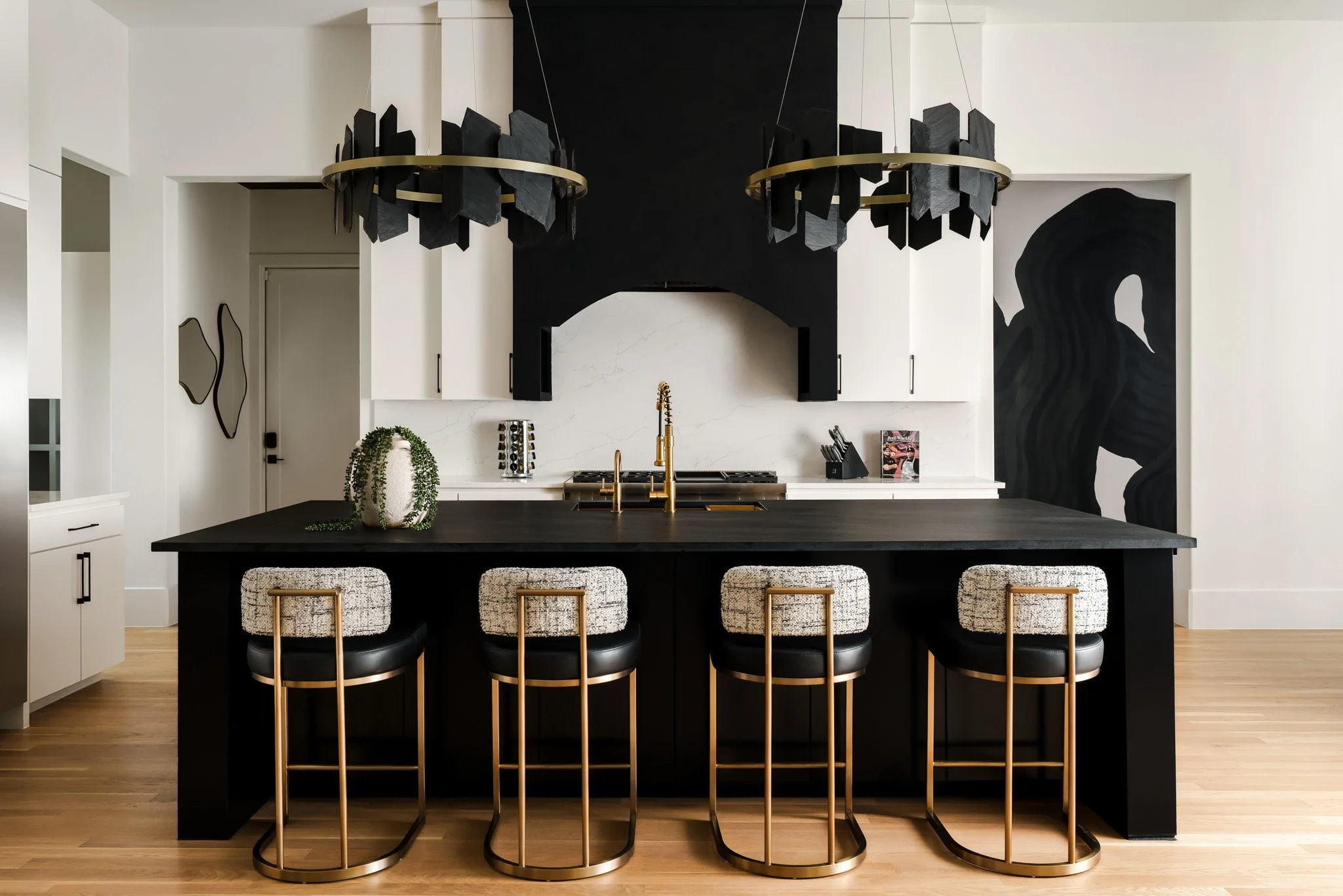 Black and white kitchen with bold hood vent and brass accents. Design by Travis Pernell Interiors and Kea Interiors 