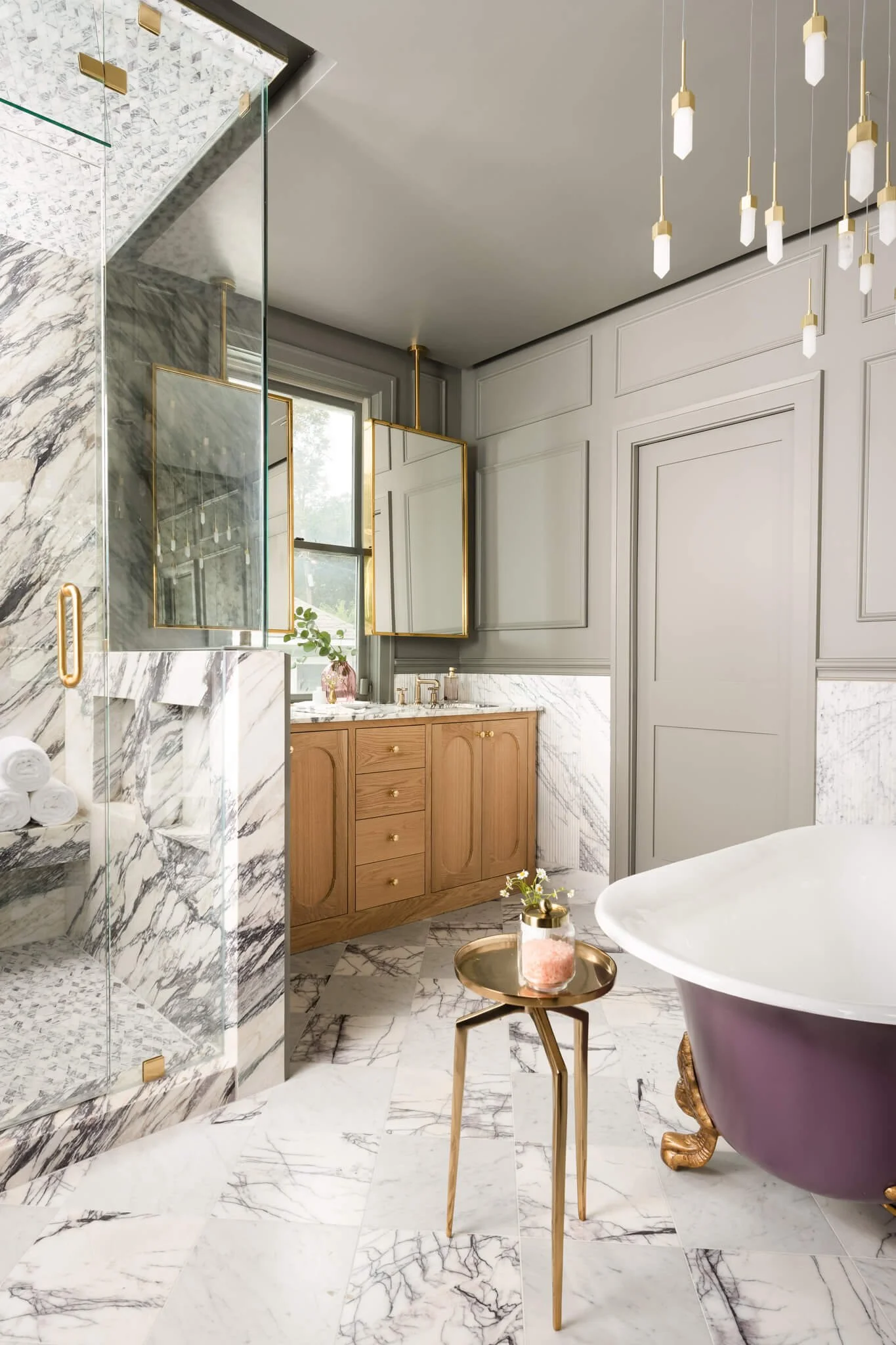 Marble bathroom interior with freestanding soaking tub, walk-in shower, and warm wood vanity photographed in Dallas.