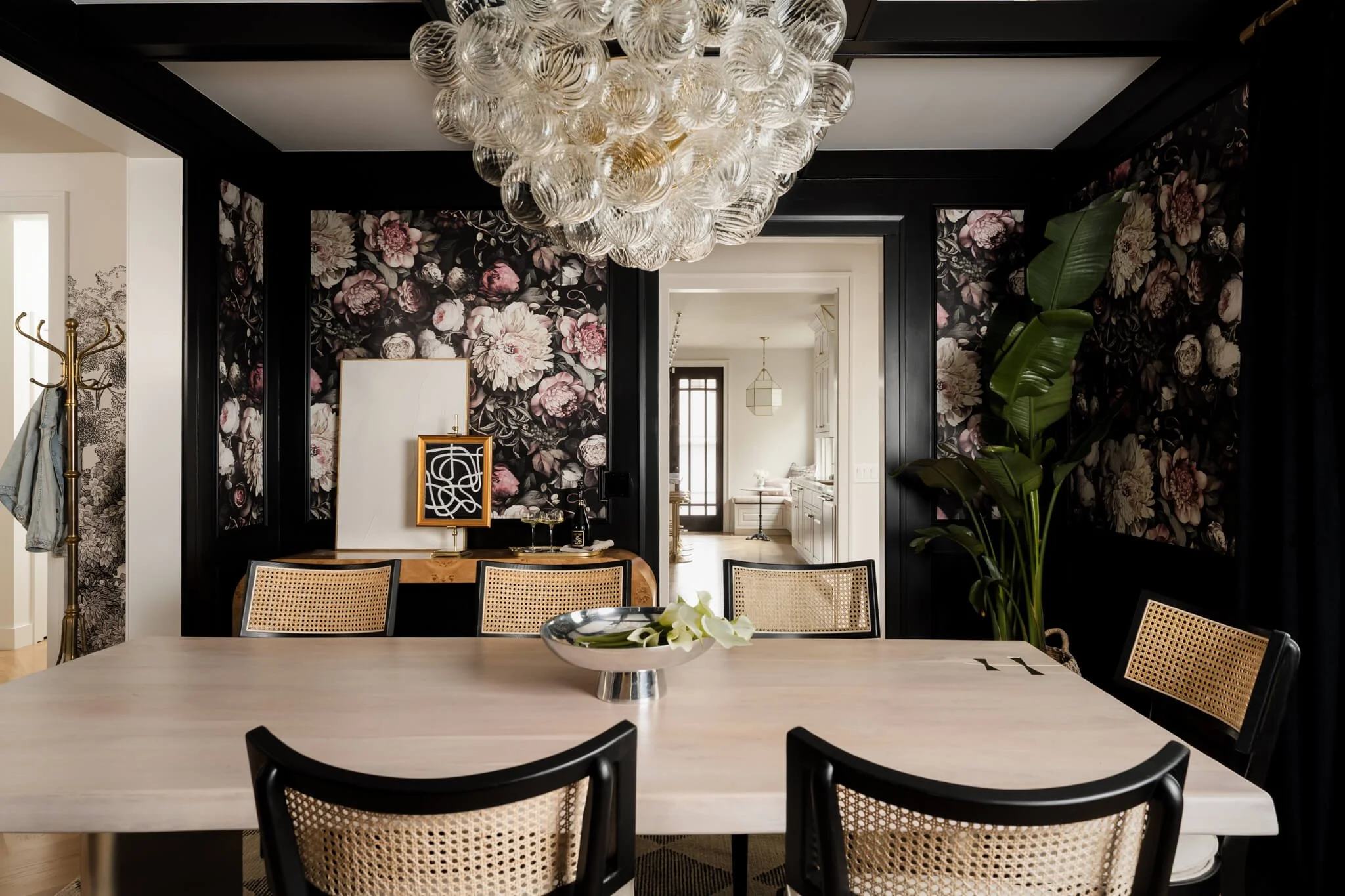 Luxury dining space with oversized sculptural chandelier, floral wallpaper, and dark modern millwork in a Texas interior design project.