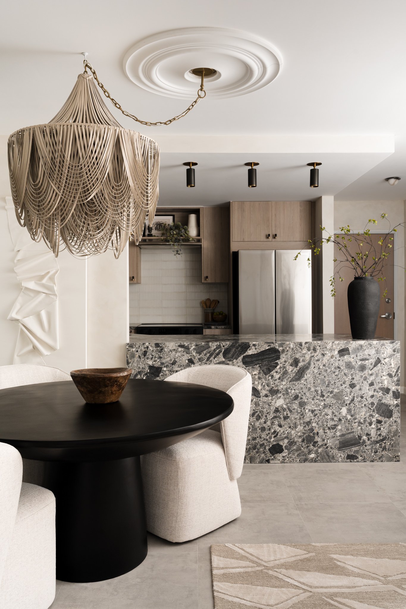 dining room with black pedestal table, fringed leather chandelier 
