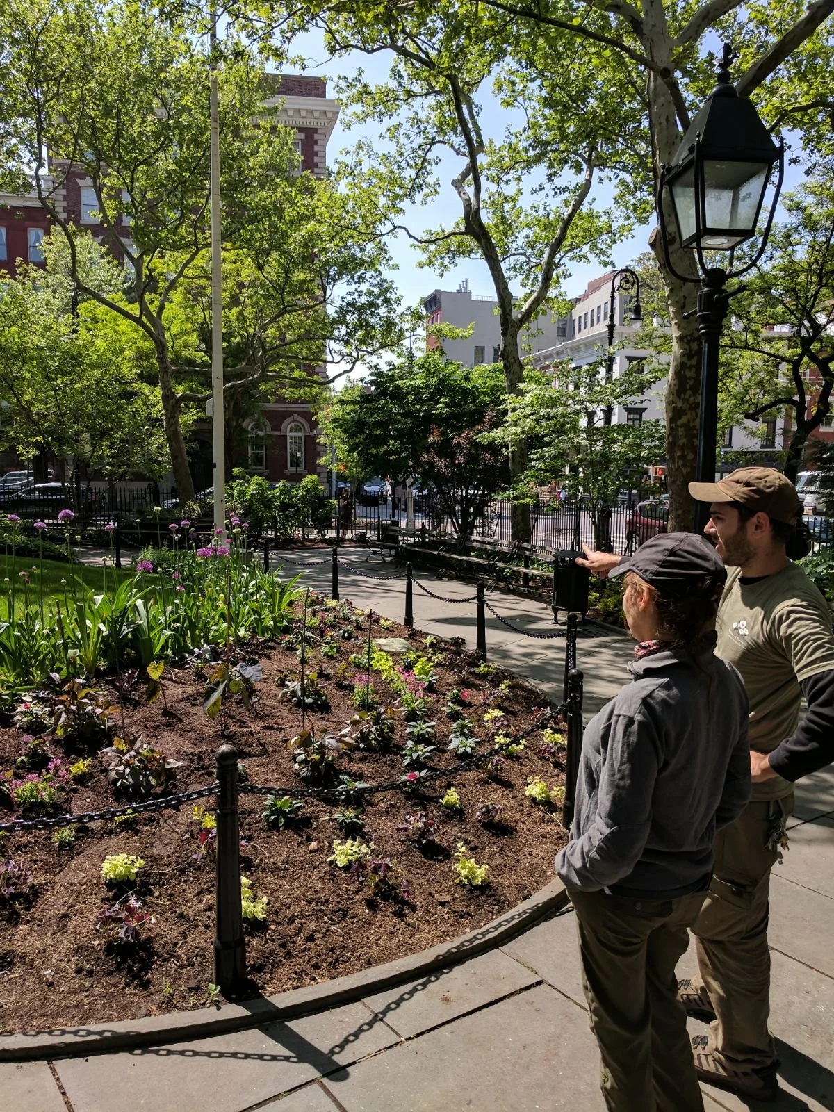 Watercolor floral arrangement with pink roses, yellow sunflowers, orange and yellow ranunculus, small pink flowers, and green leaves on a black background.