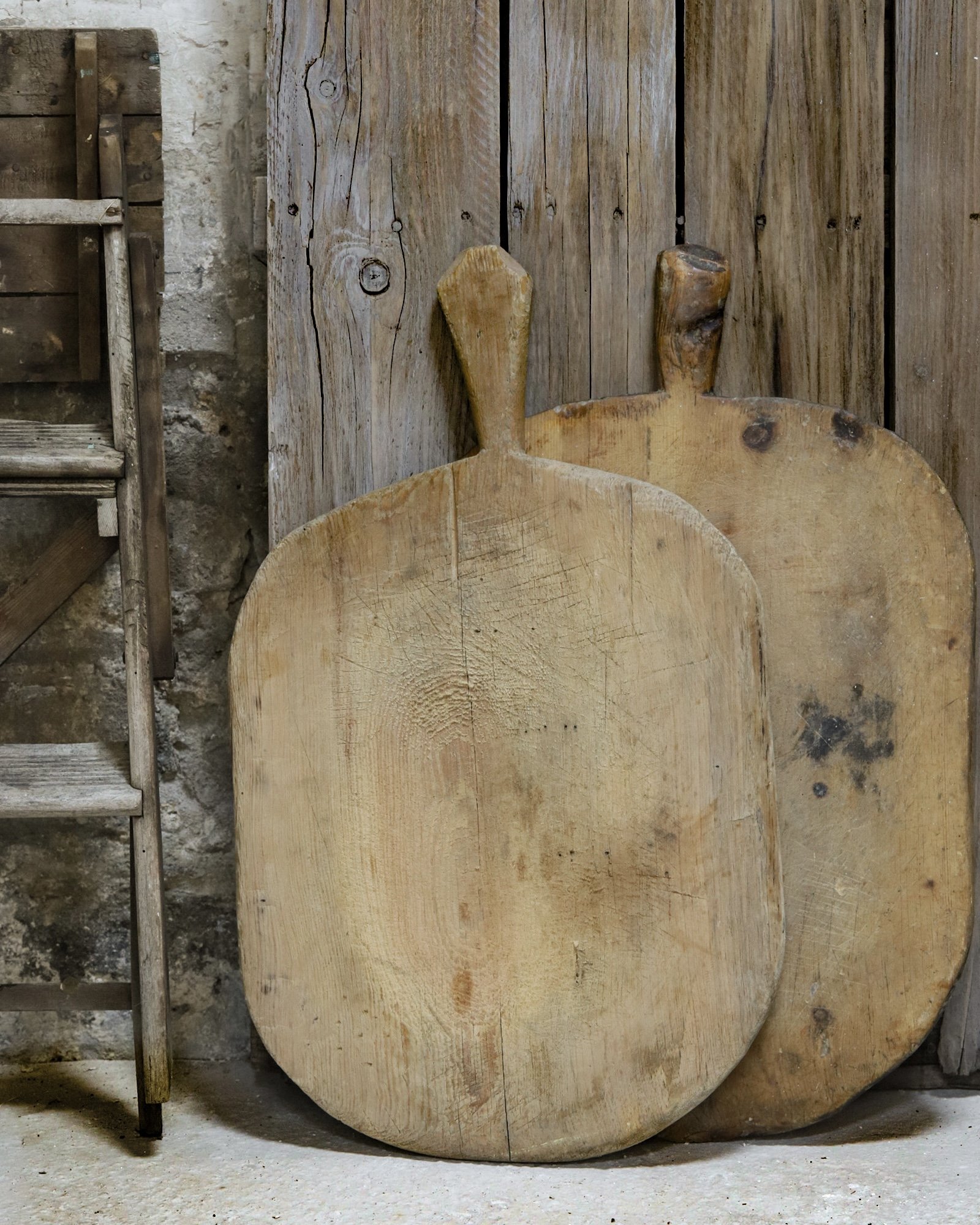 A pair of vintage European breadboards stacked against a wall