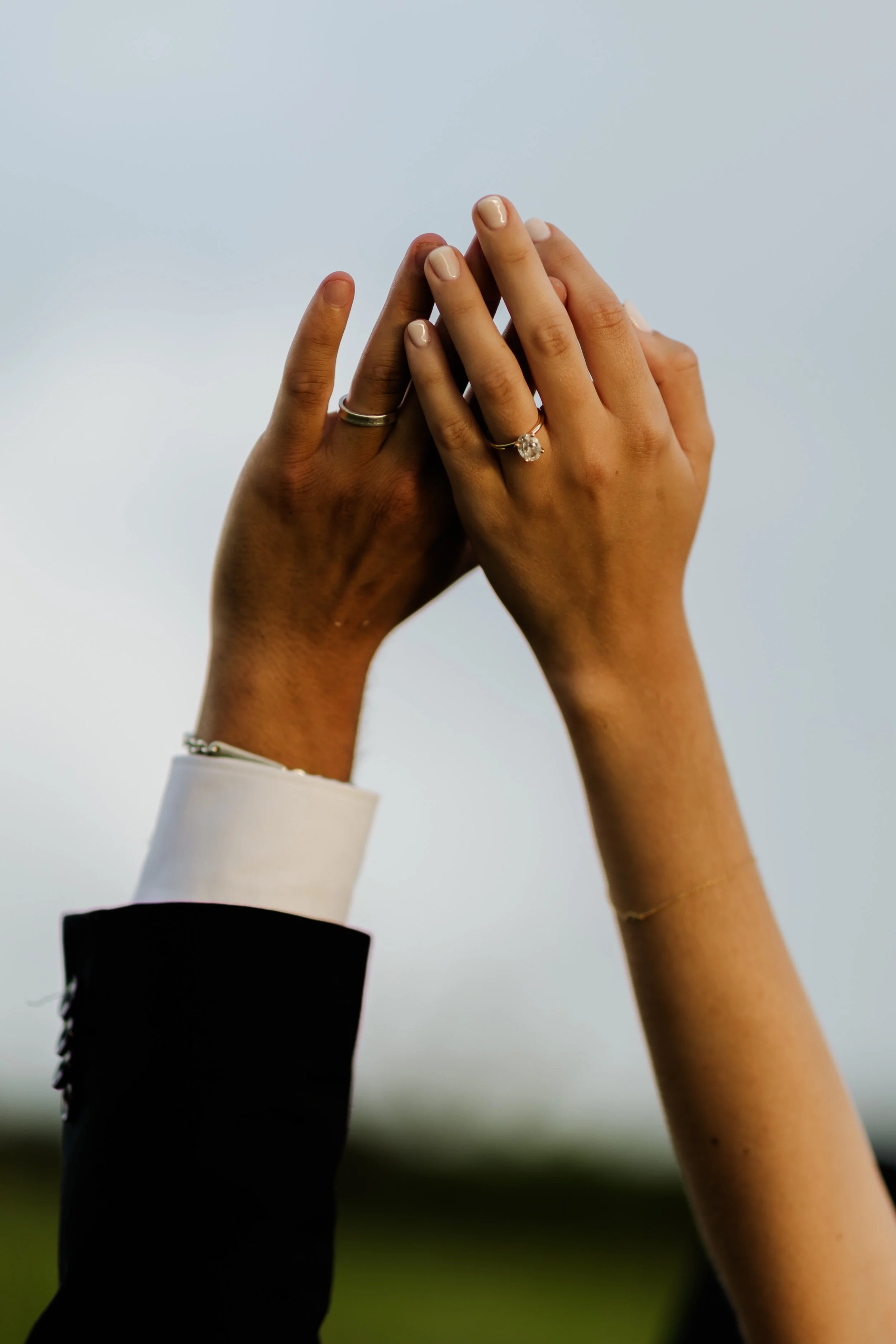 Image of two hands with rings pressing their palms together against a plain white background.