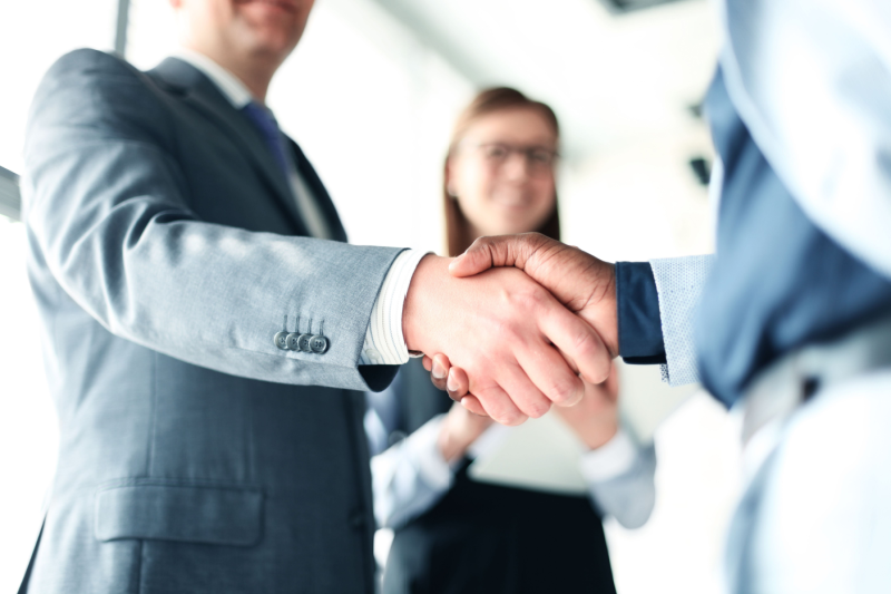 Business professionals shaking hands after a client referral.