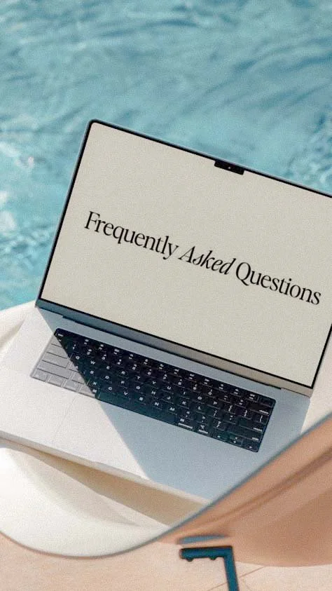 Laptop displaying 'Frequently Asked Questions' on screen, placed on a surface near a swimming pool.