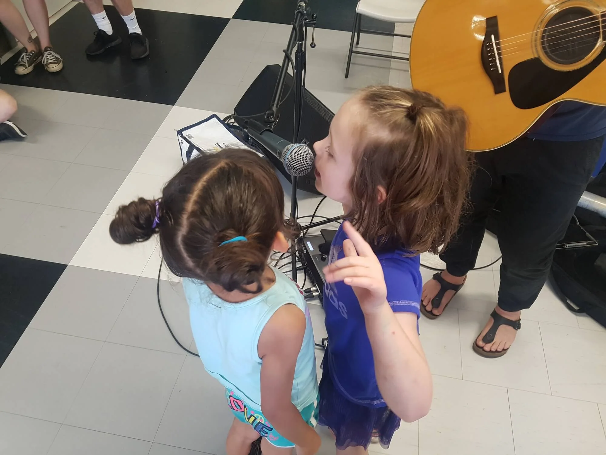 Two young girls singing into a microphone during a BGC London program