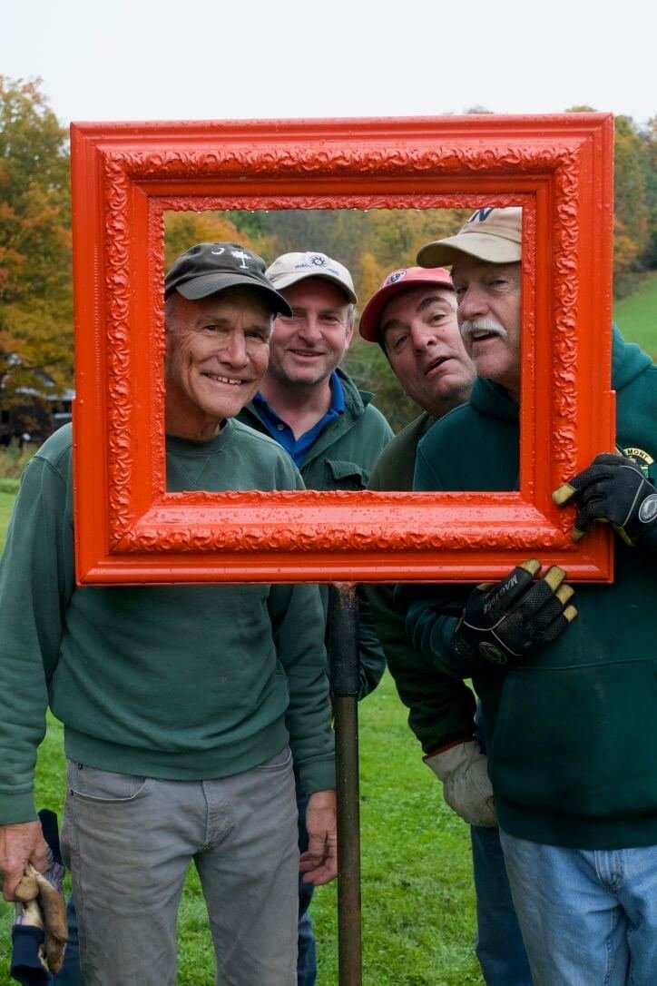 Four men looking through a red picture frame.