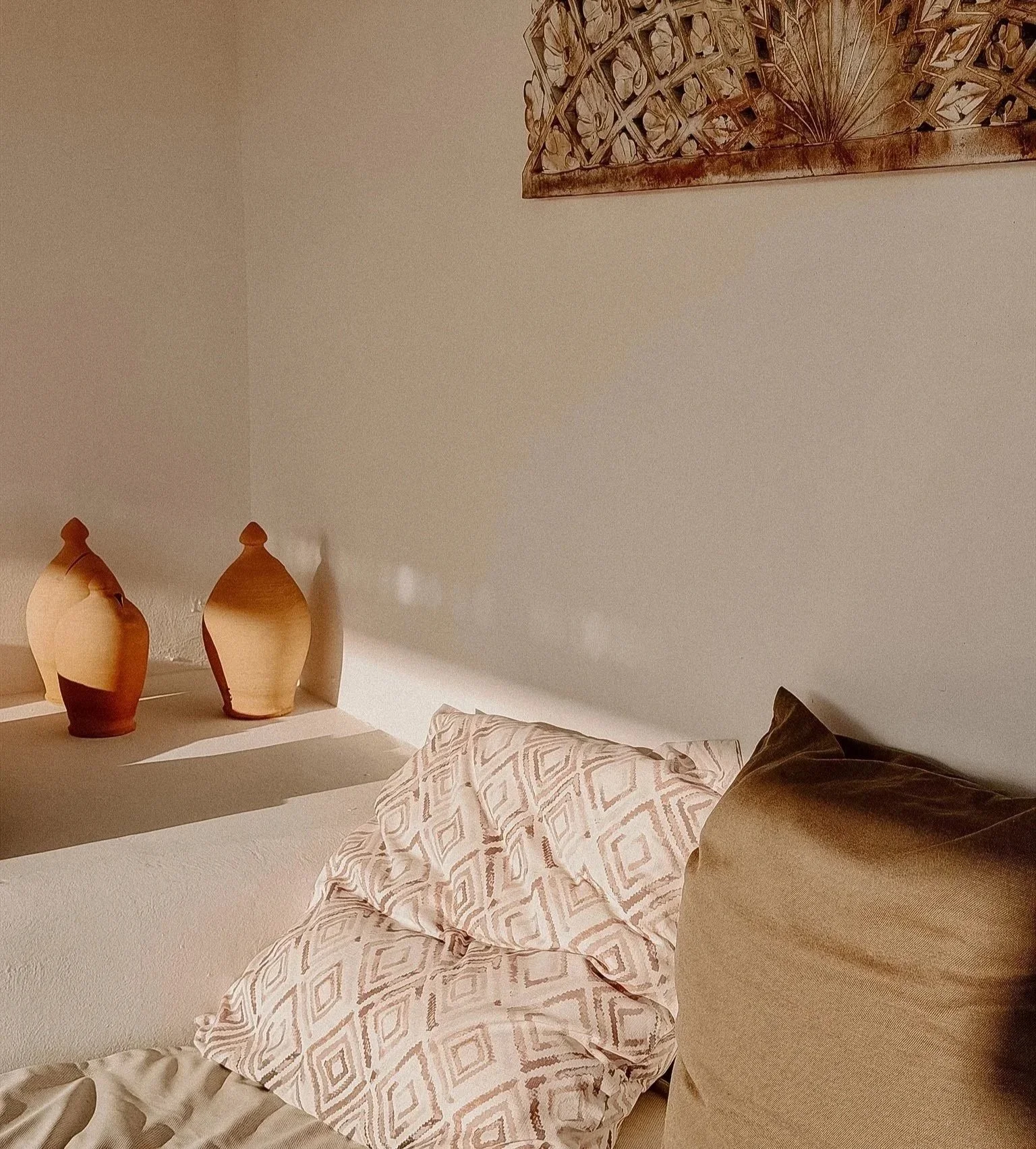 Mallorquinisches Flair: Eine Couch mit Kissen, an der Wand drei dekorative Keramikvasen, an der oberen Wand ein Wandbild aus Holz.