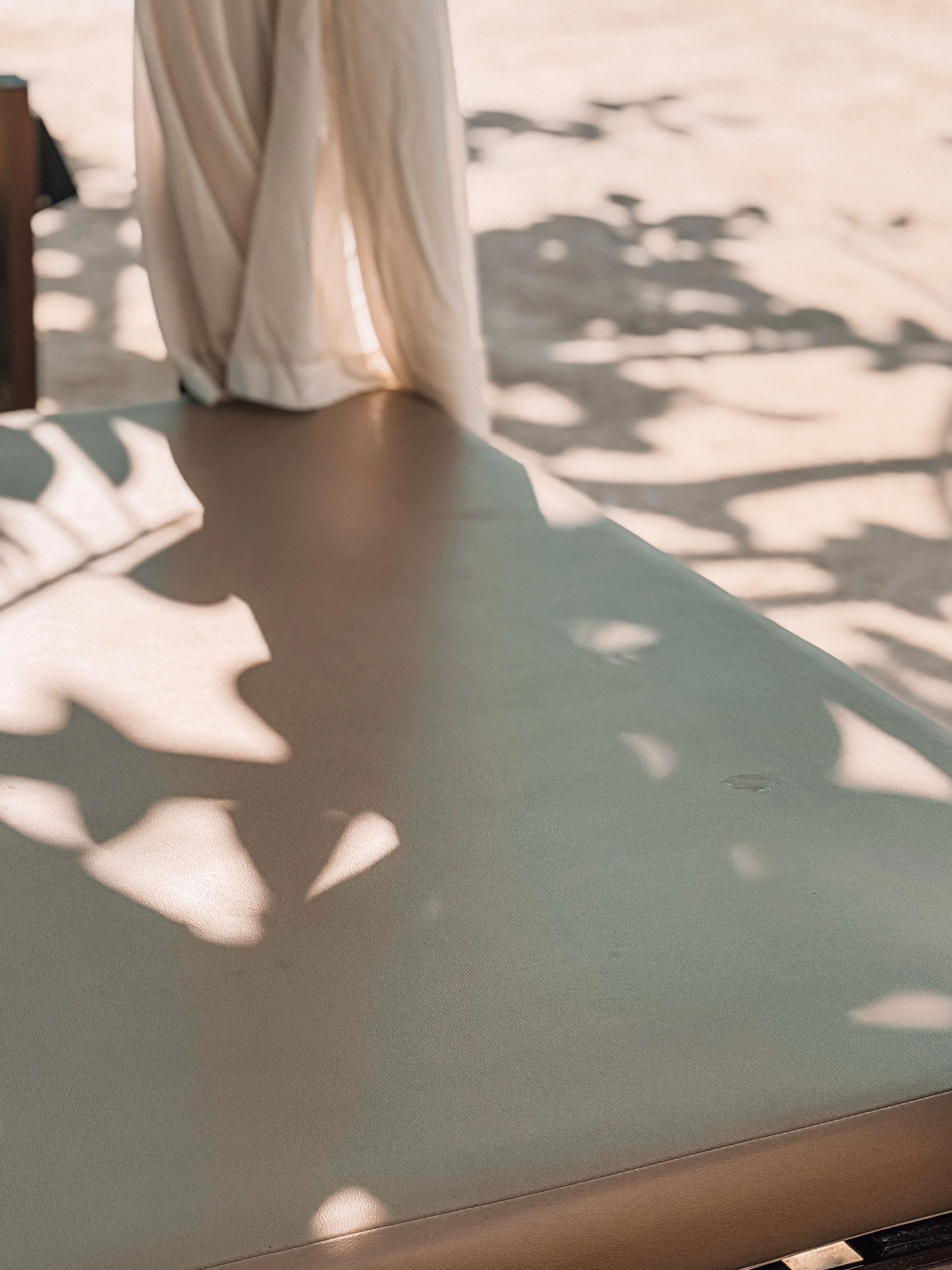 Sonnengeschützte Terrasse mit Schatten von Blättern auf einem Tisch