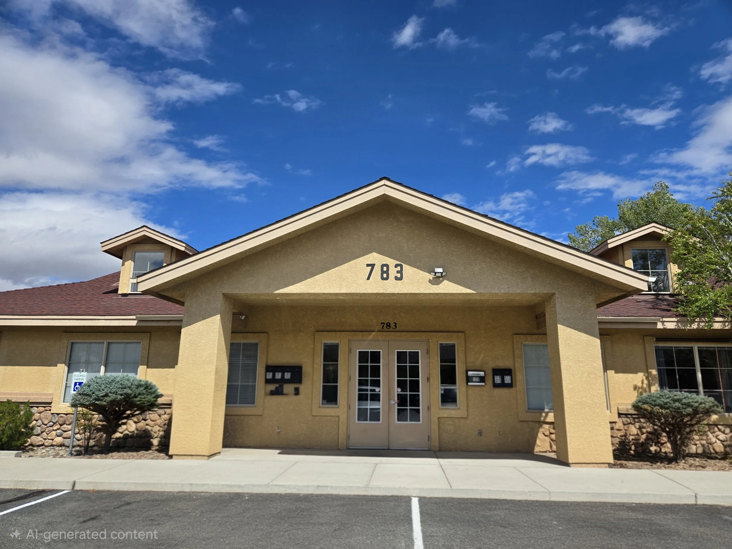 Front view of a beige office building with the number 783, two small dormer windows, and a red-shingled roof, under a partly cloudy sky.