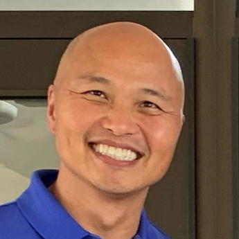 Smiling man with a shaved head wearing a blue shirt
