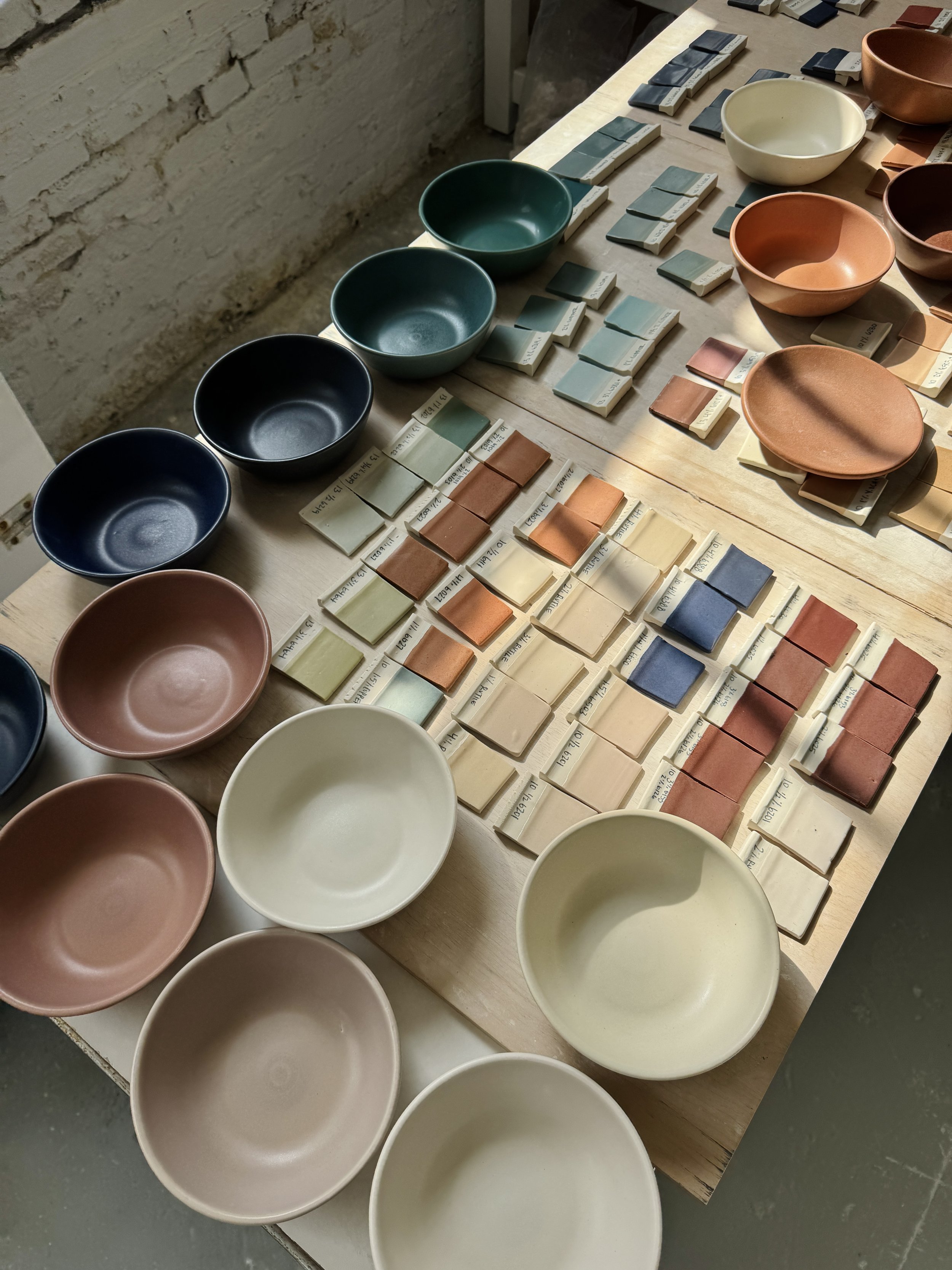 Fired porcelain test tiles laid out and sorted by color direction.